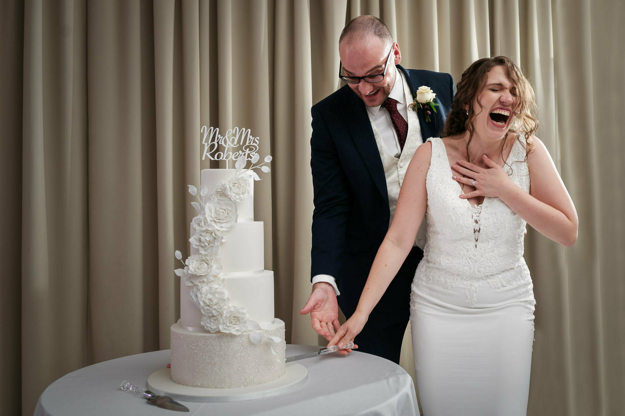 Bride and groom laughing during the cutting of the cake at Aubrey Park Hotel