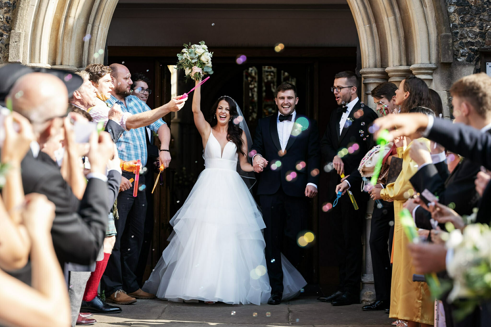 The bride and groom exit the church in Berkhamsted with bubbles filling the air