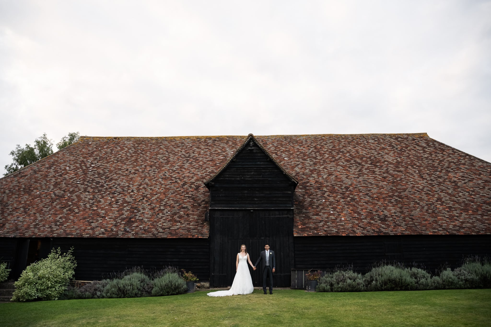 Relaxed portrait of bride and groom with The Priory in Little Wymondley in the background