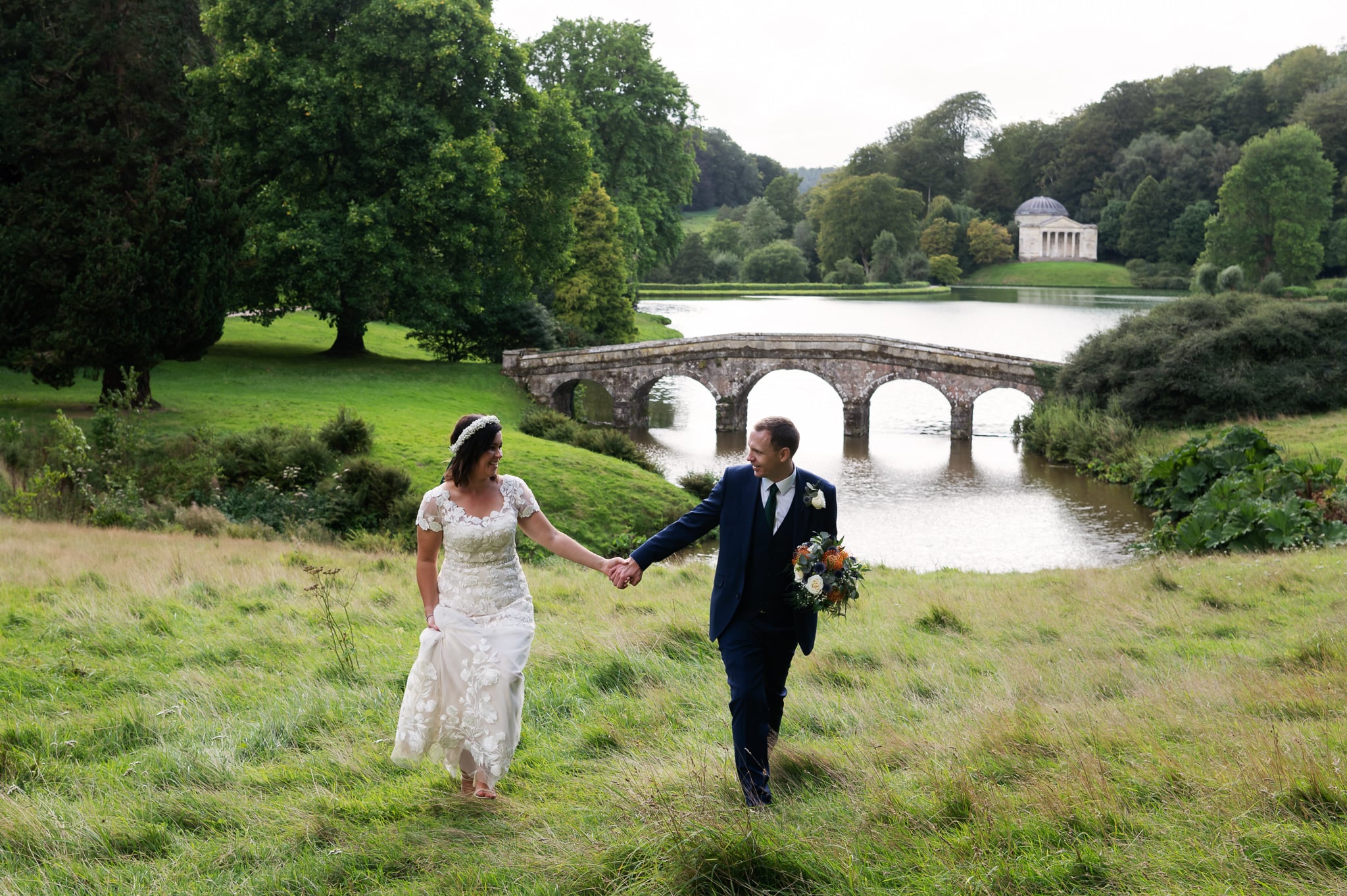 A wedding portrait of the bride and groom walking in the grounds of Stourhead