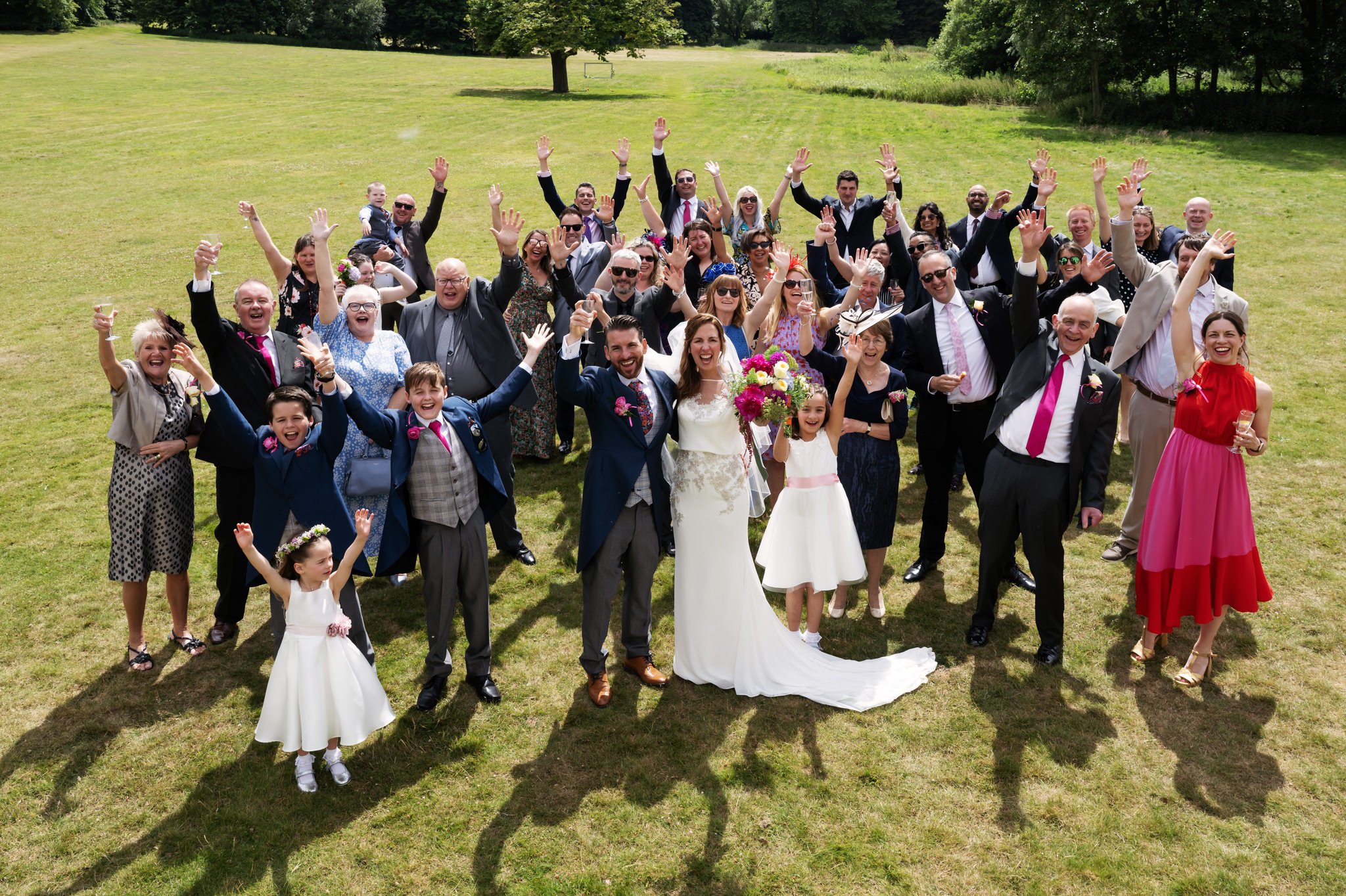 A group photo of the bride and groom with all their wedding guests at Hitchin Priory.