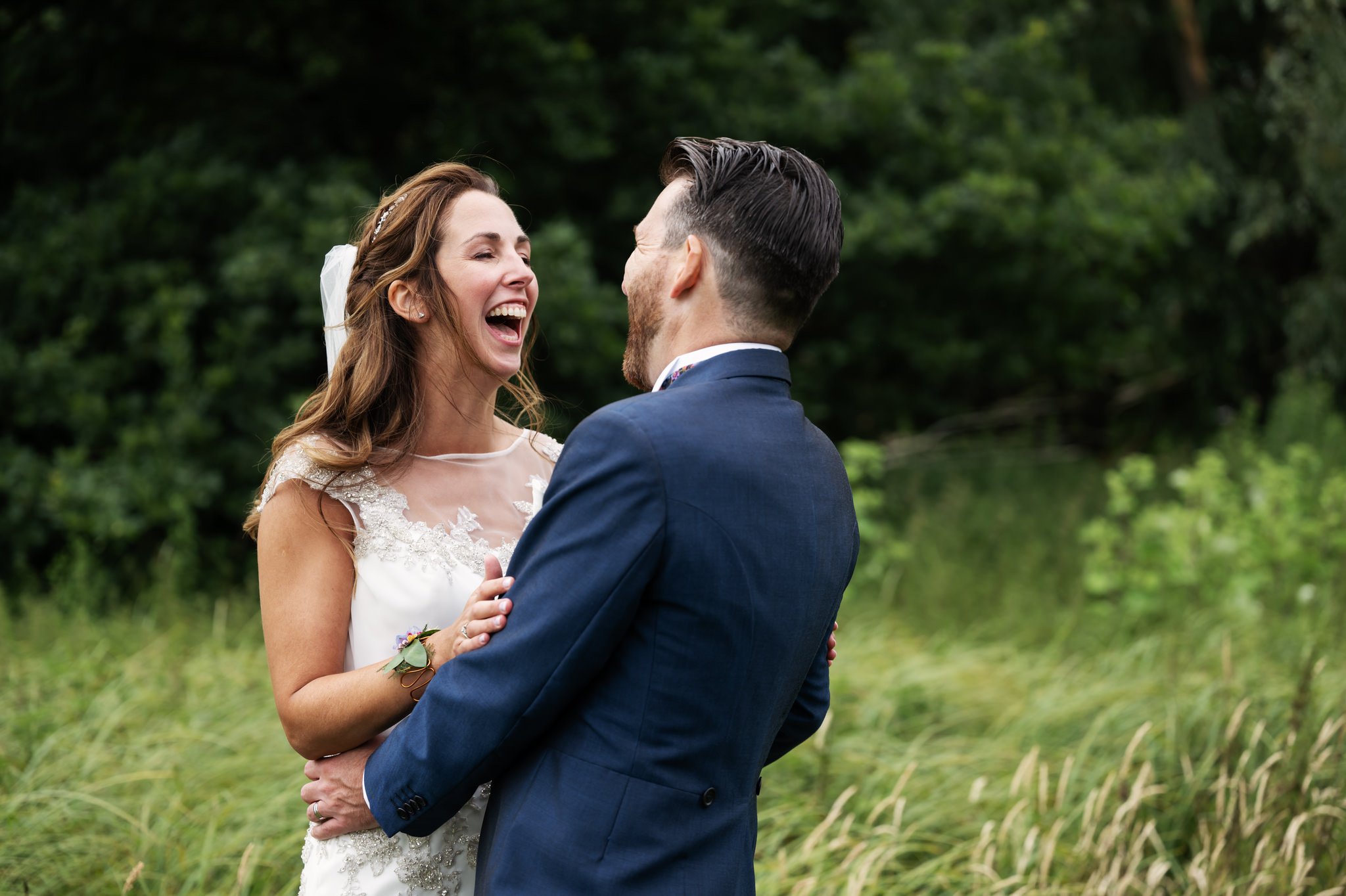A fun and relaxed portrait of the bride and groom laughing at their Hitchin Priory wedding.