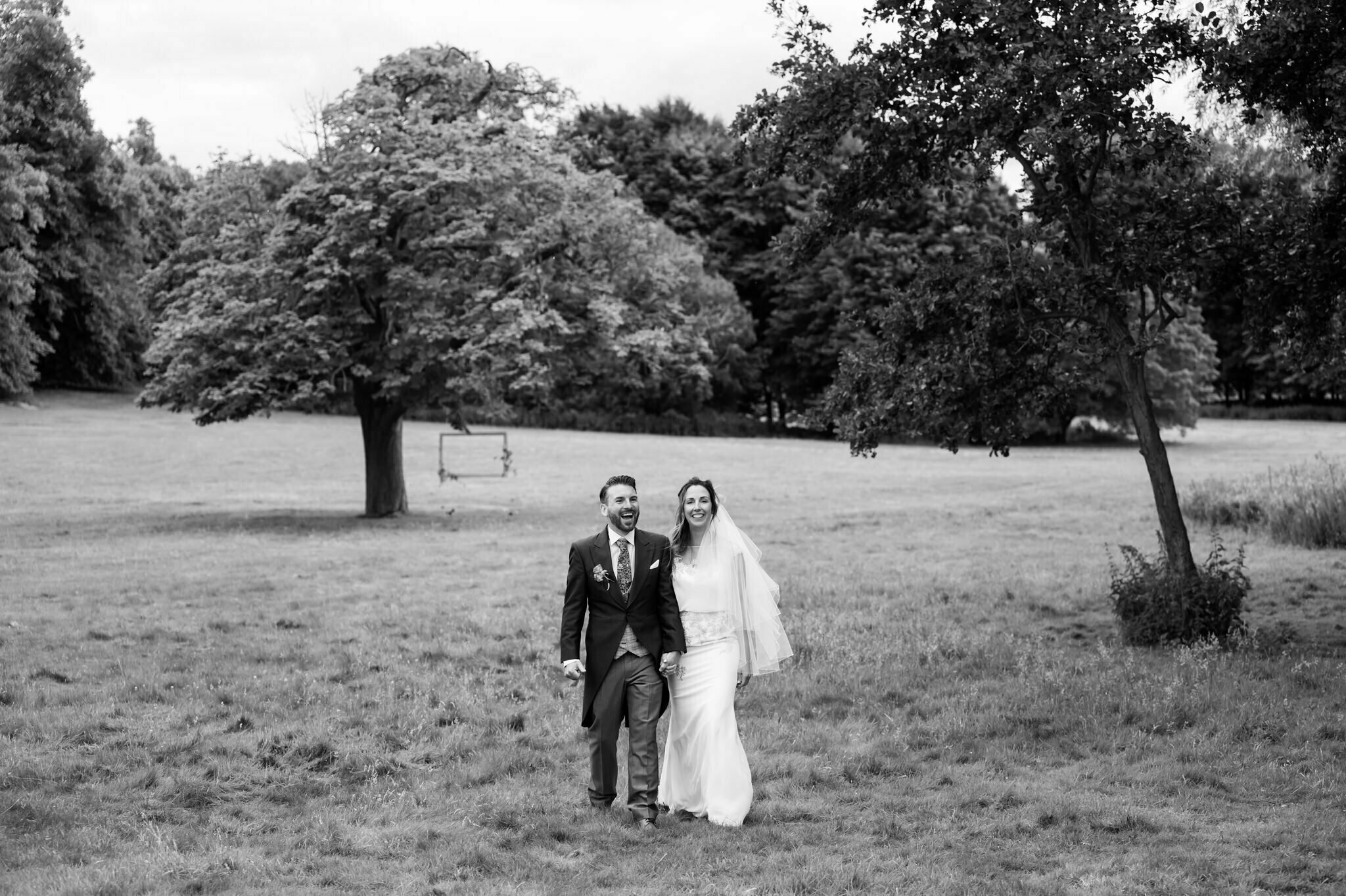 A portrait of the bride and groom walking in the grounds of Hitchin Priory.