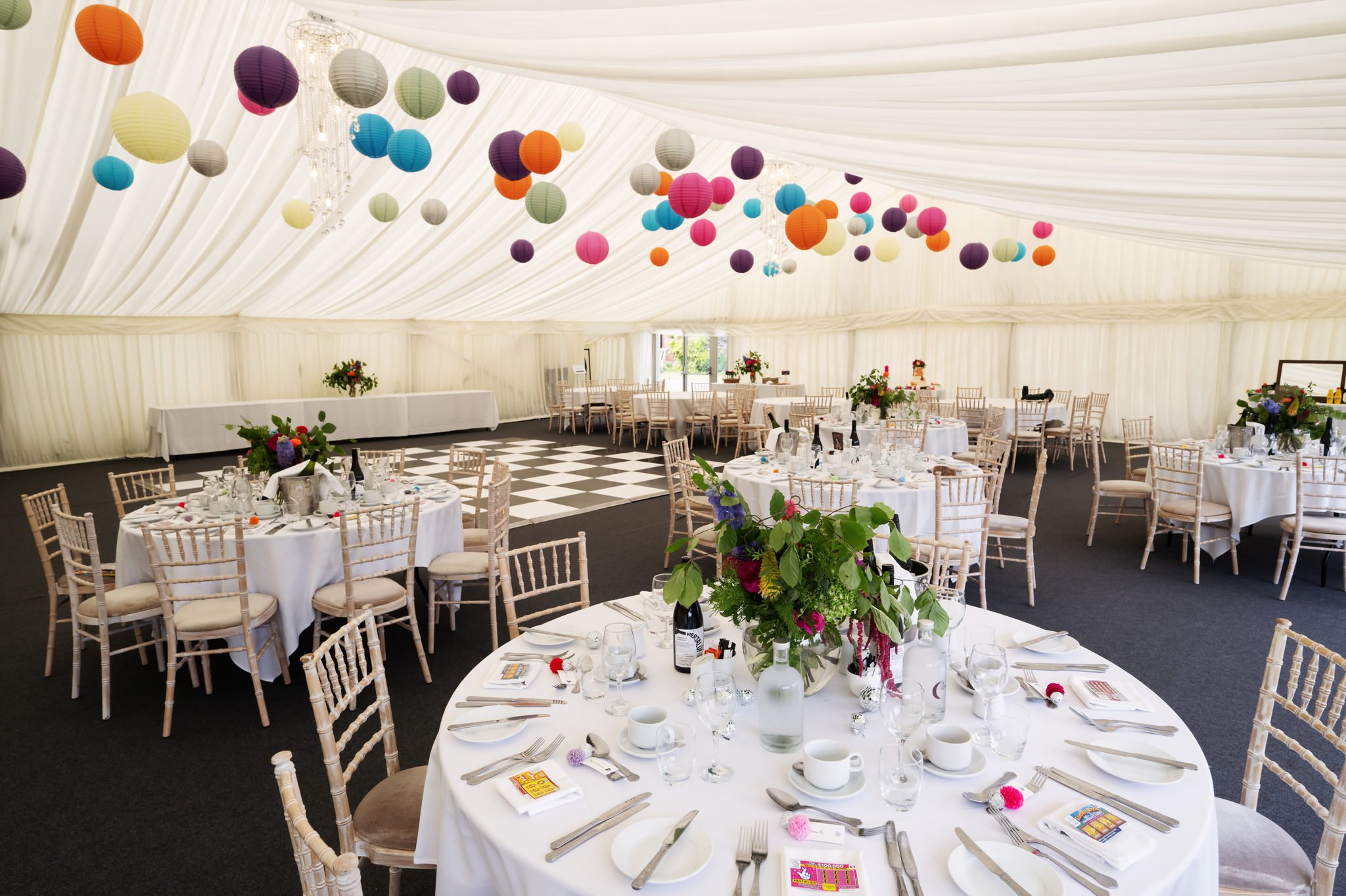 The marquee at Hitchin Priory decorated with colourful lanterns and colourful flowers.