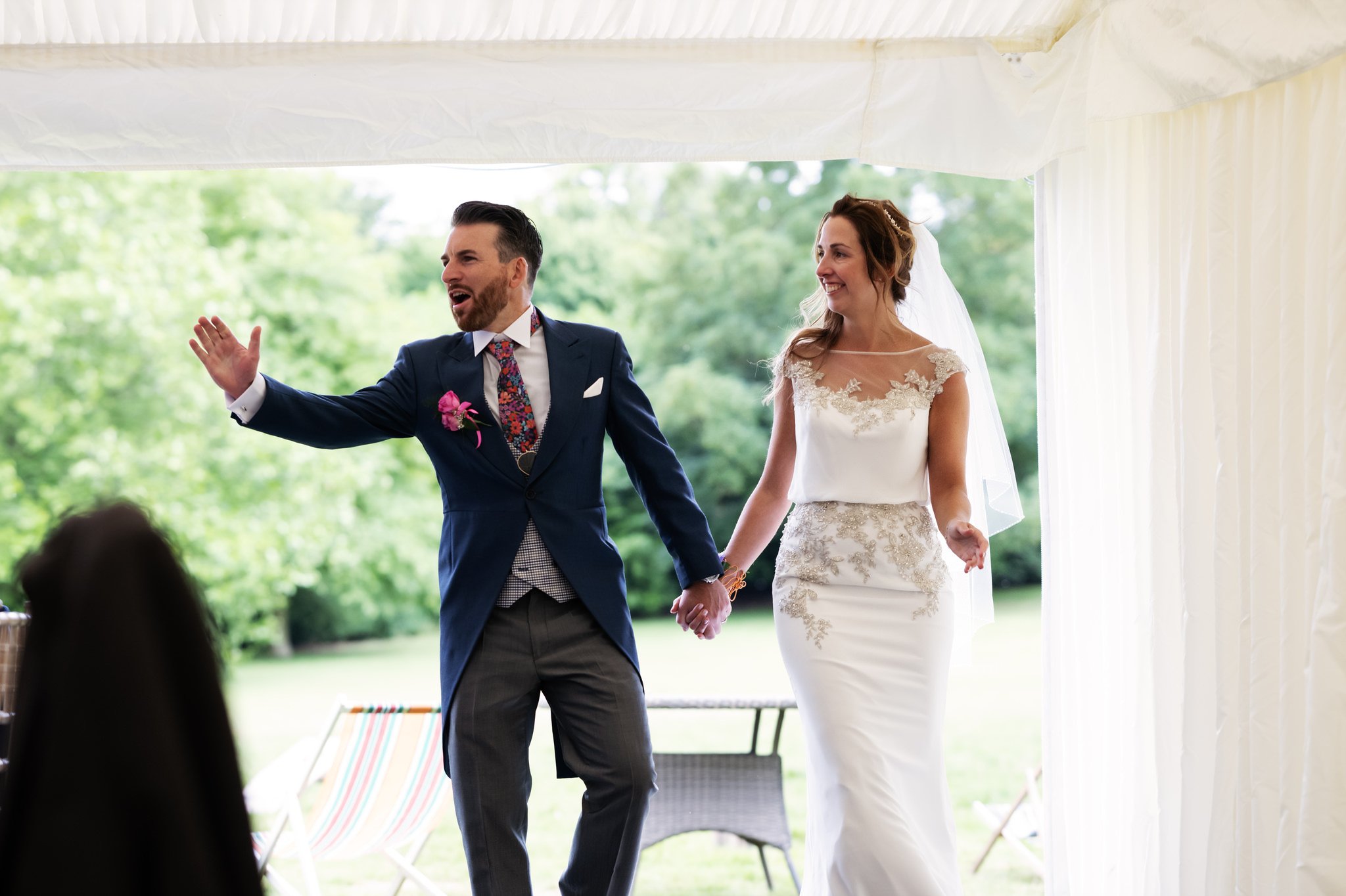 The bride and groom enter the Marquee at Hitchin Priory.