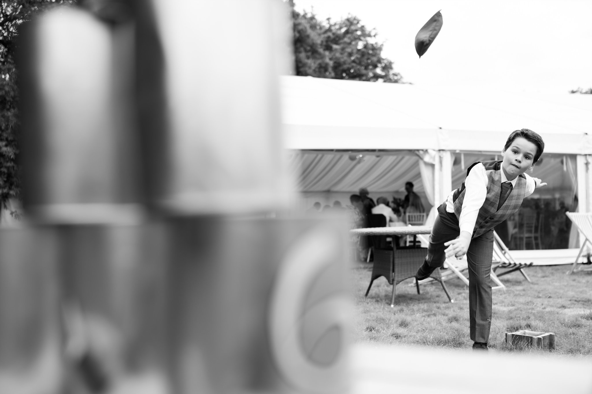 A young wedding guest throwing bean bag at a tin can alley.