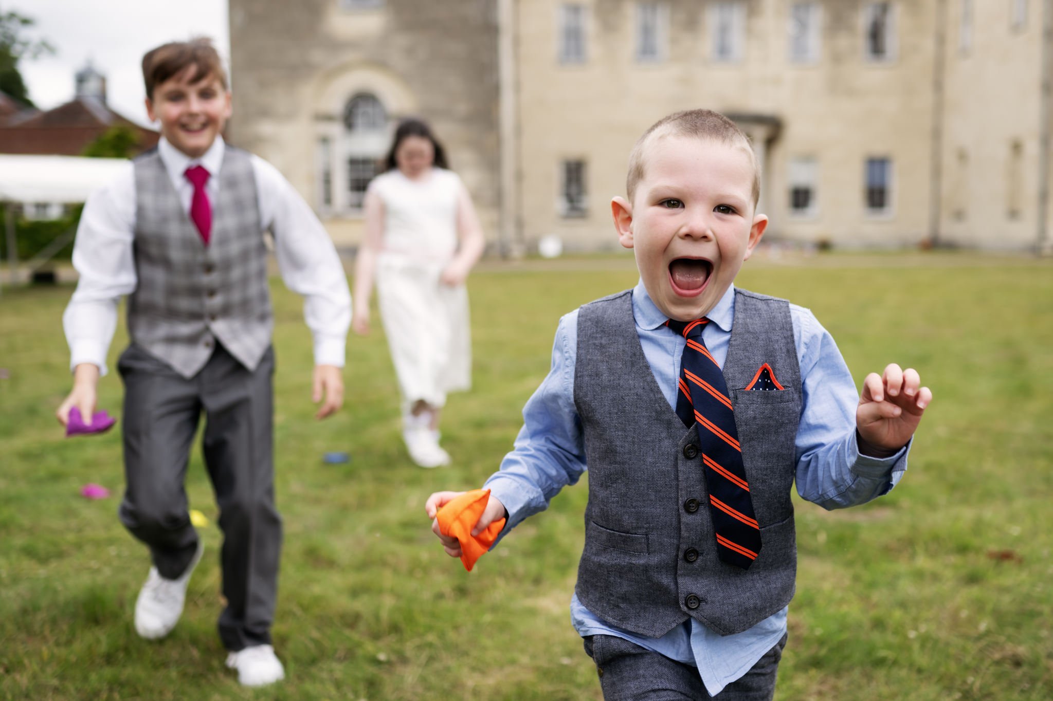 Three kids playing with bean bags during a a wedding reception at Hitchin Priory.