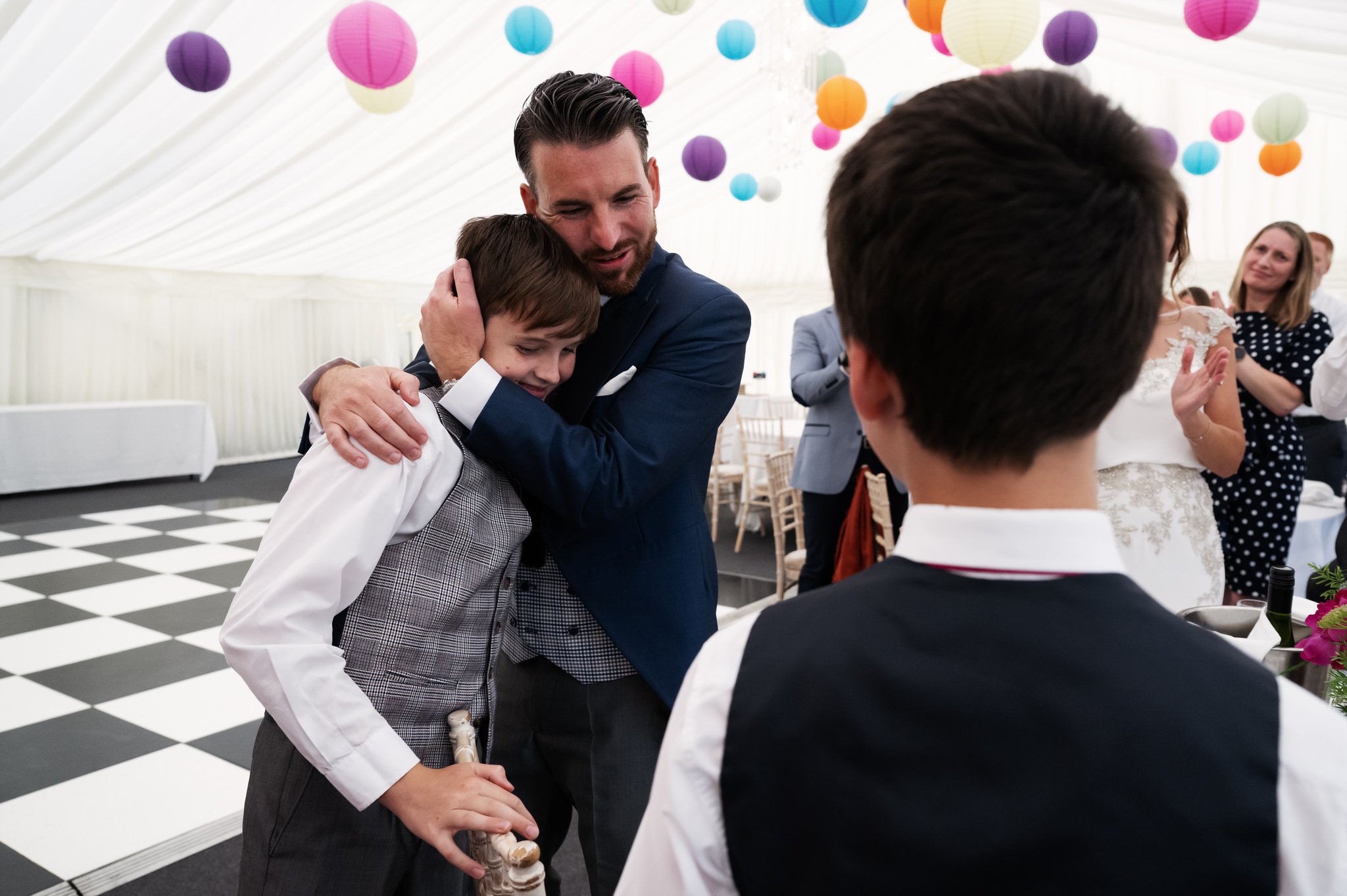 The groom hugs his son after his son speech.