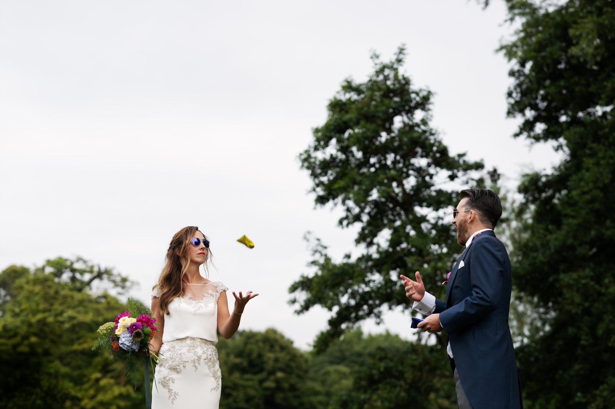 A candid photo of the bride and groom throwing a beanbag to each other.