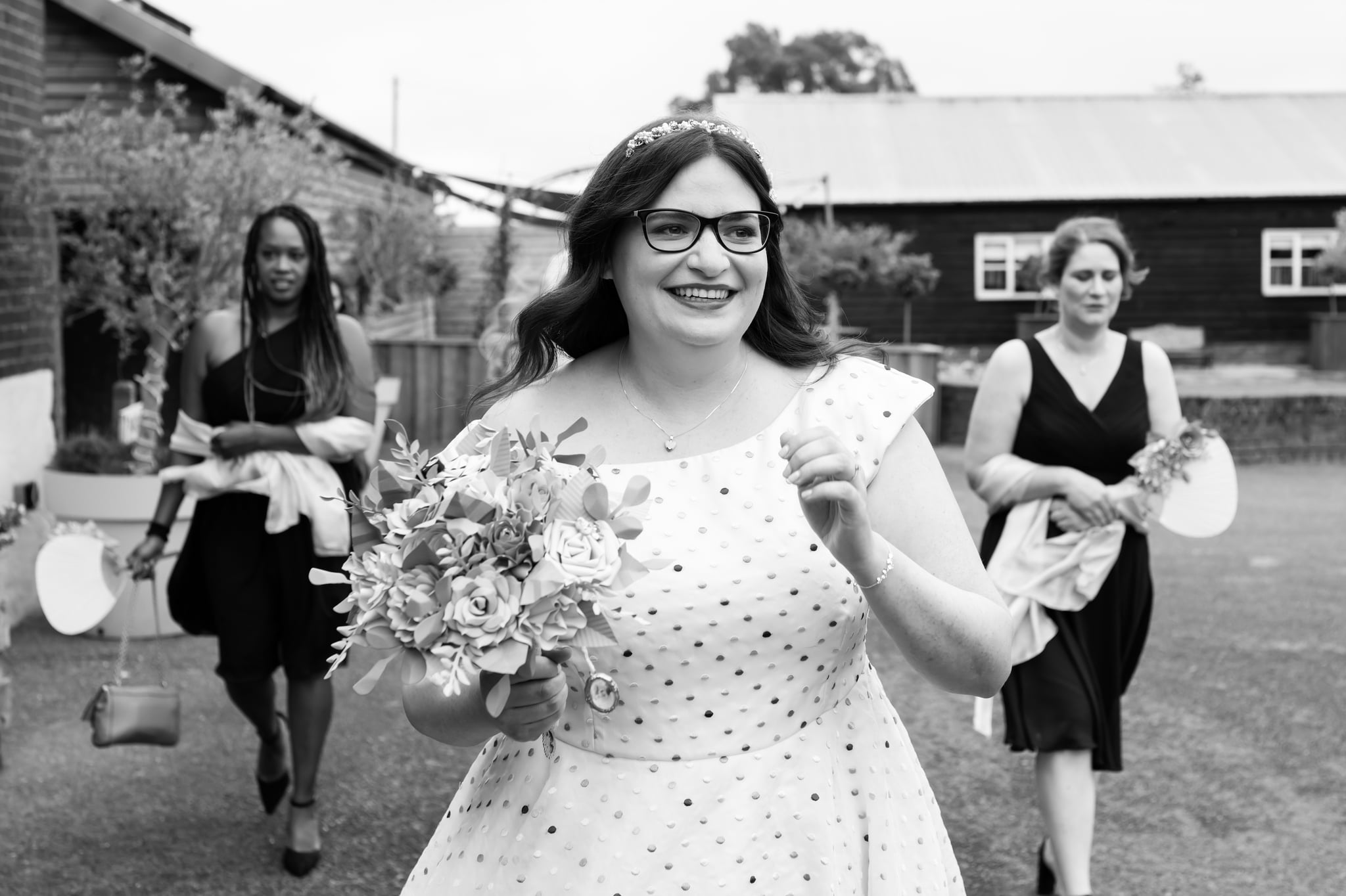 The Bride walks towards the barn for the wedding ceremony with her bridesmaids following her in the background.