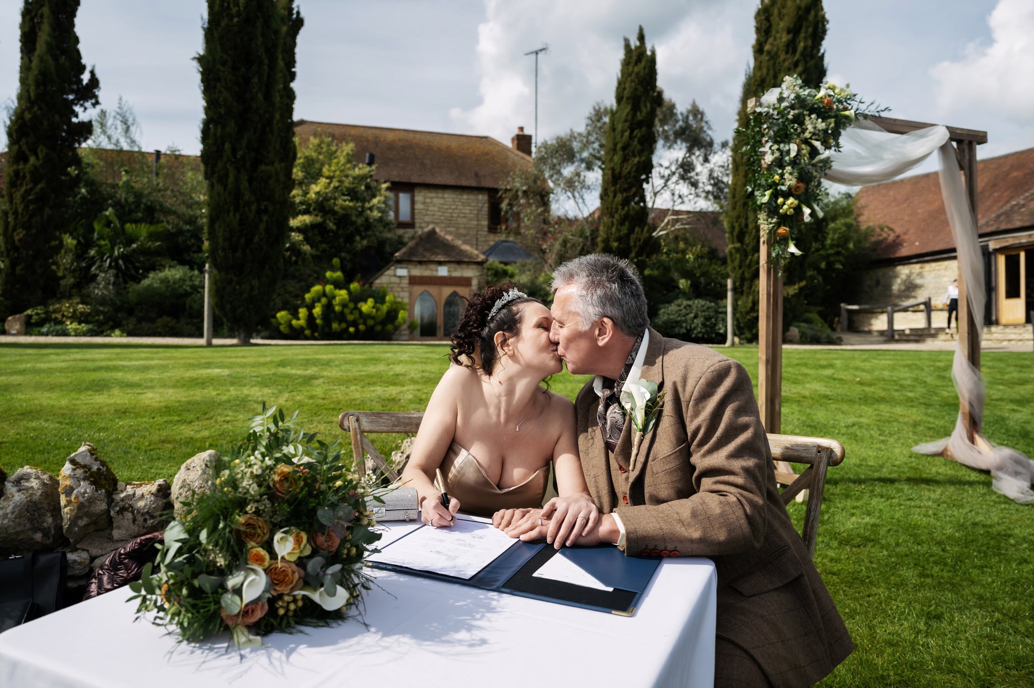The bride and groom kiss while signing the wedding register.