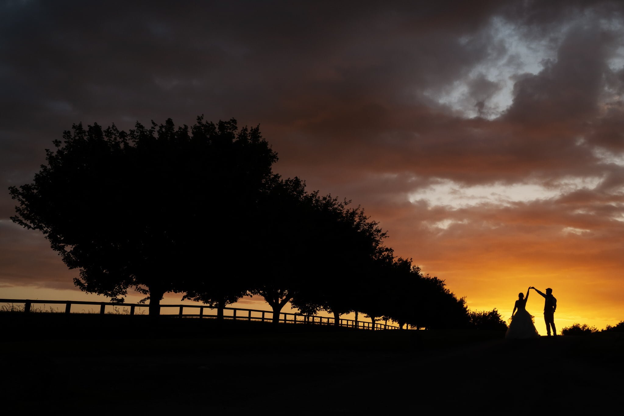 A silhouette of the bride and groom at sunset on their wedding day at Notley Tythe Barn.