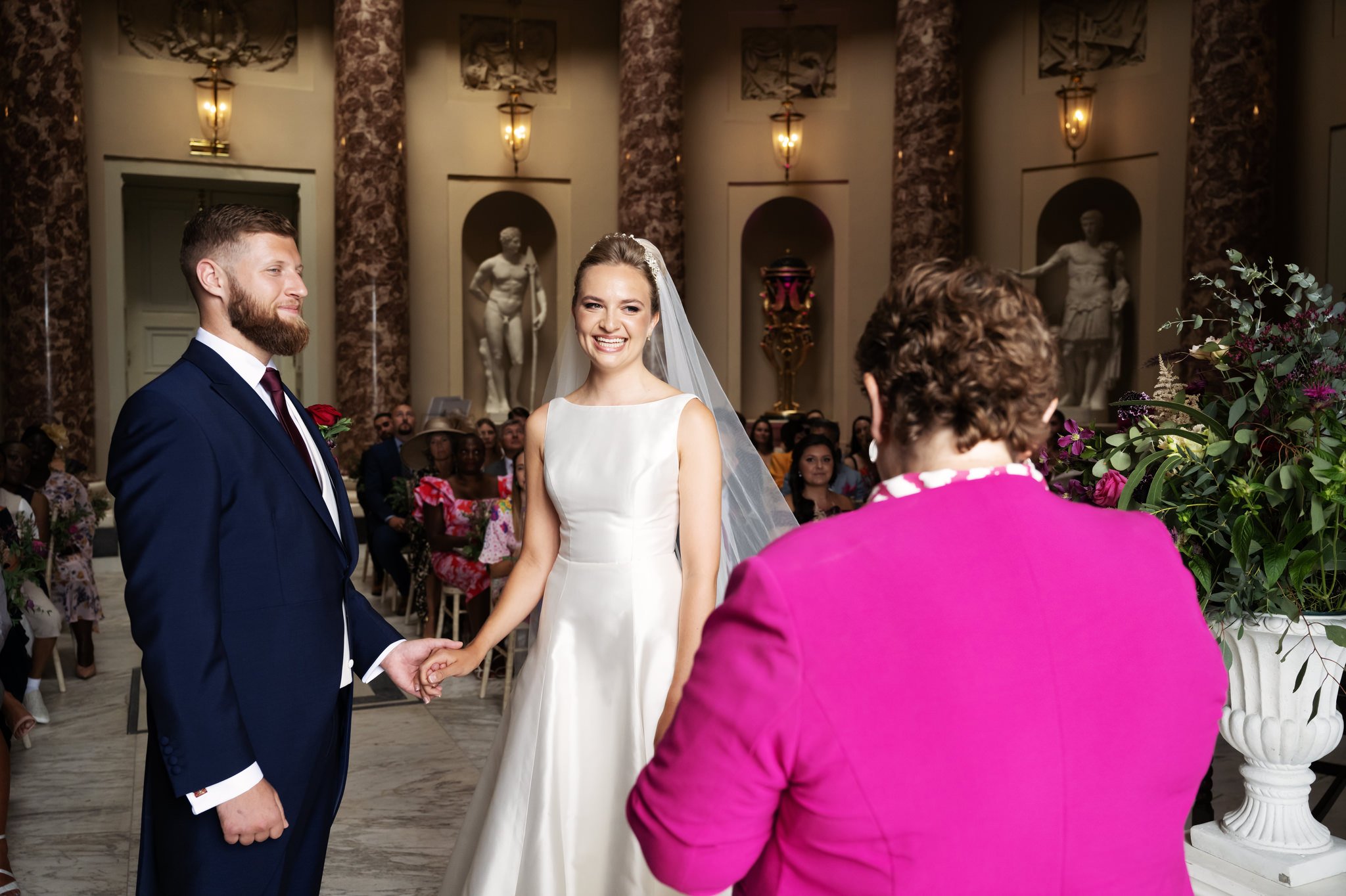 The bride and groom hold hands during the wedding ceremony at Stowe House. Buckinghamshire wedding photographer.