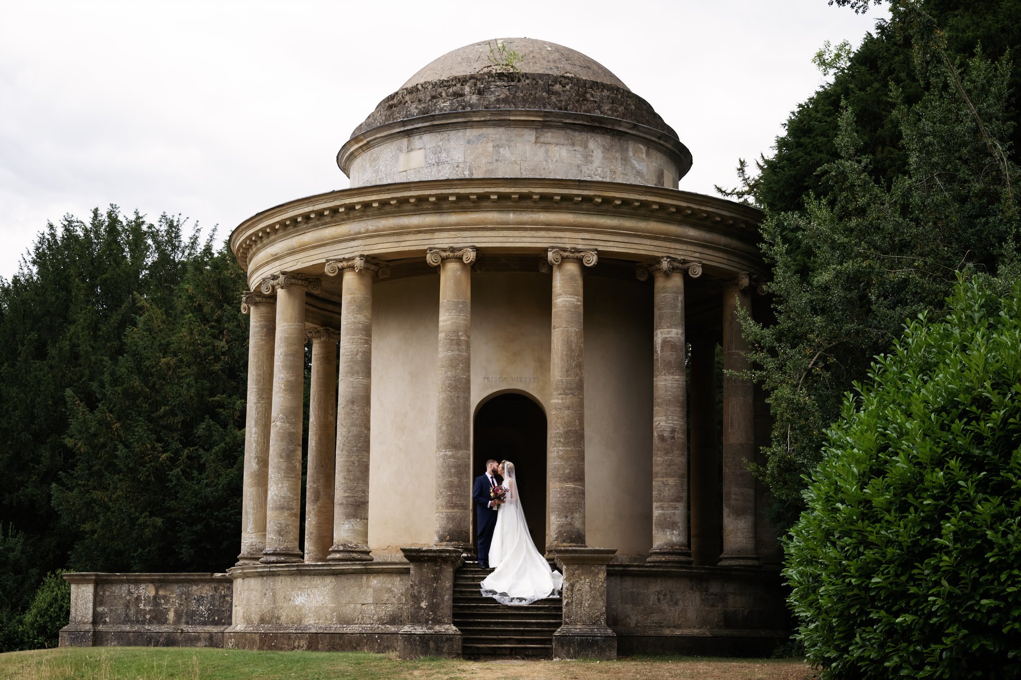 A portrait of the bride and groom on the steps of The Temple of Ancient Virtue at Stowe House.