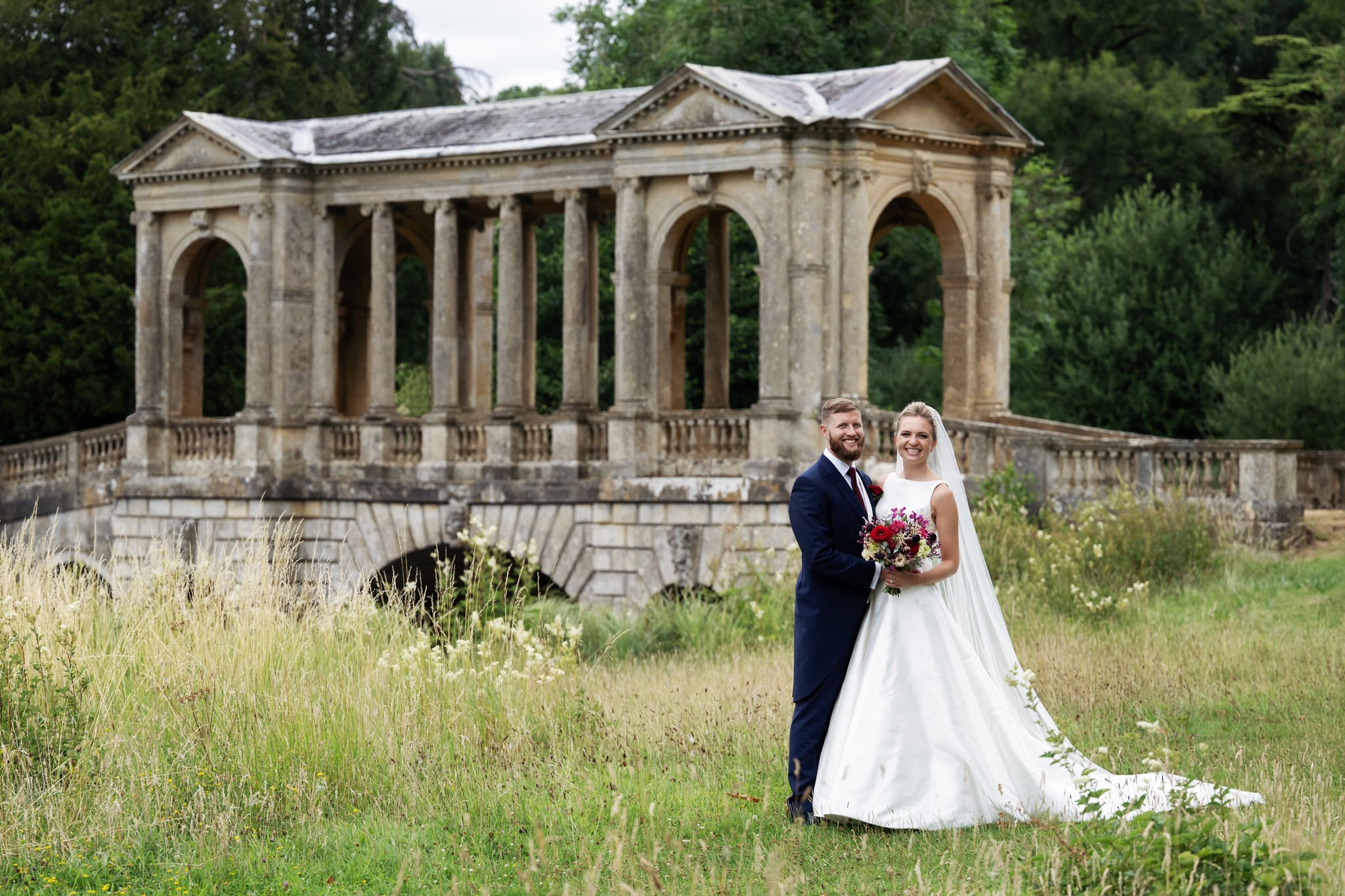 A portrait of the bride and groom in front of The Palladian Bridge at Stowe House.