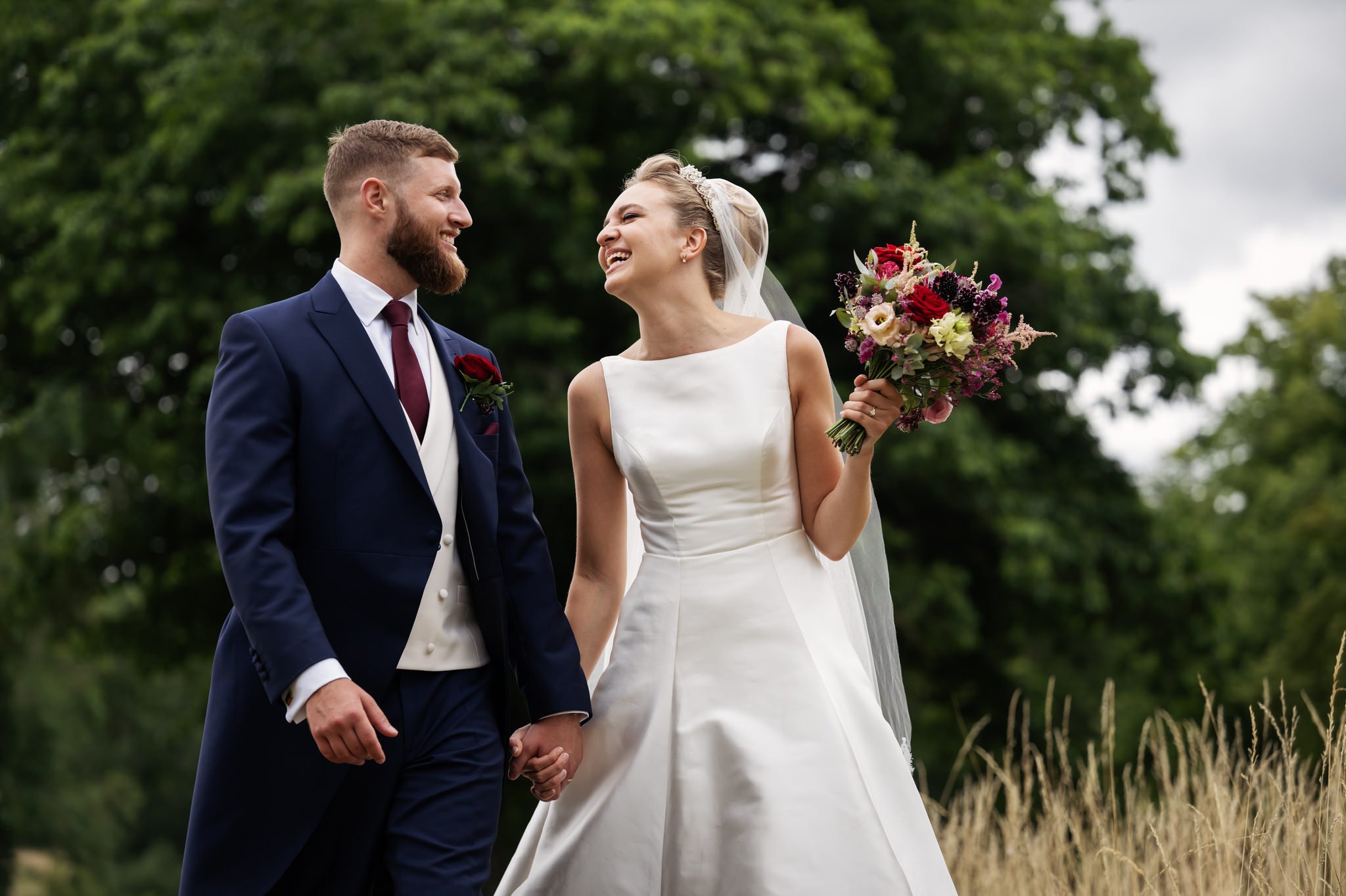 A portrait of the bride and groom walking and laughing in the grounds of Stowe House.