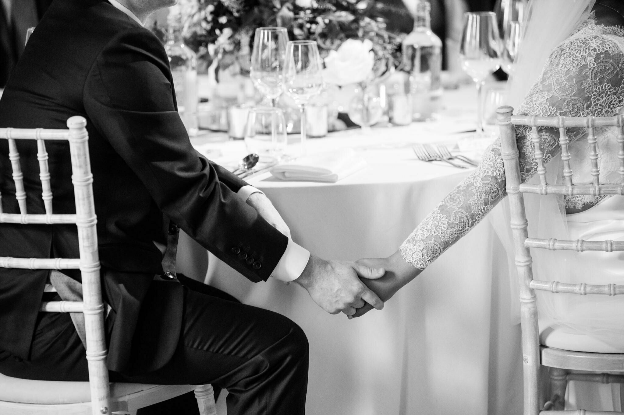 London documentary wedding photography. The bride and groom hold hands during the wedding speeches at a banqueting house wedding.