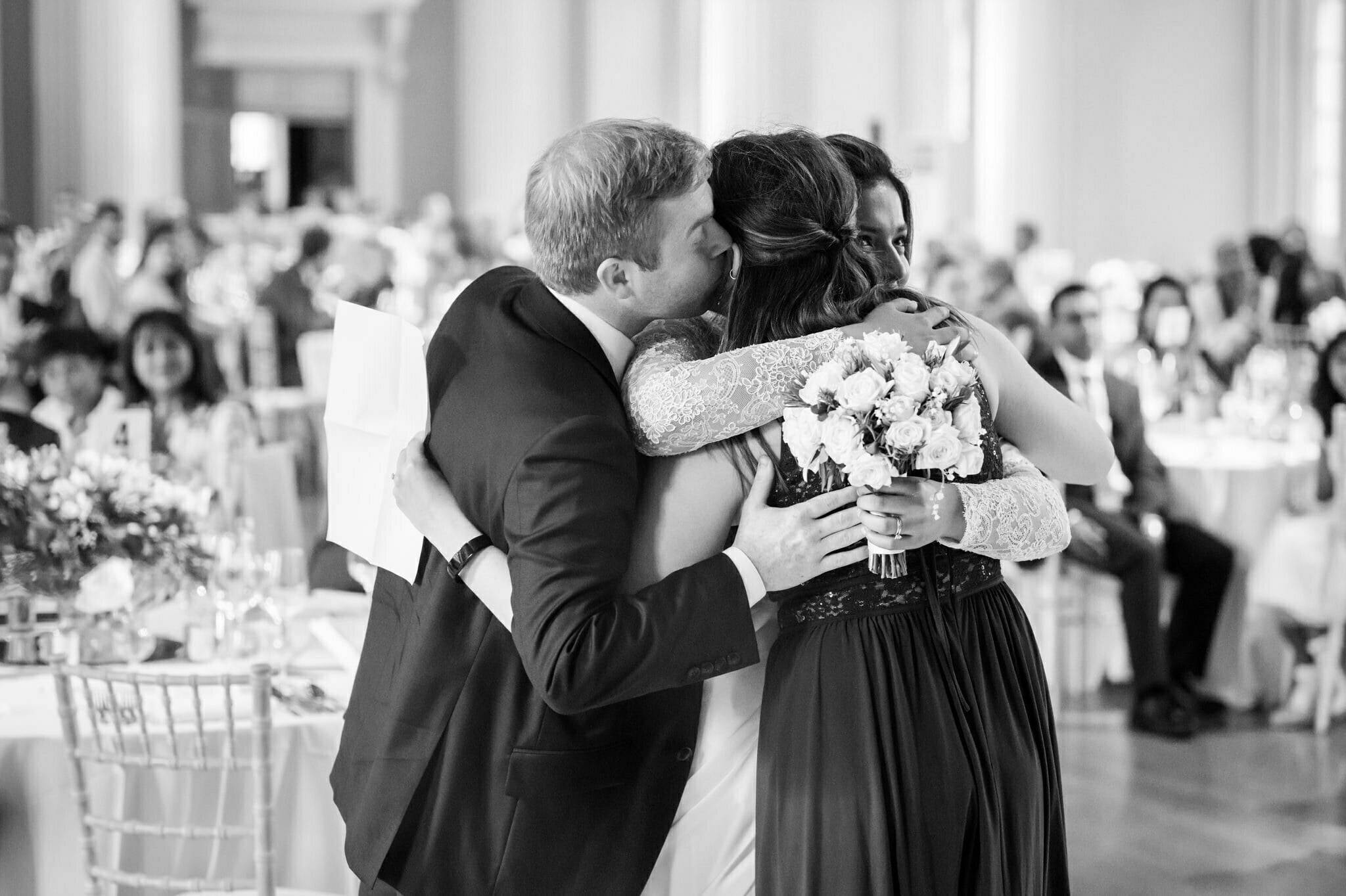 London documentary wedding photographer. The bride and groom give a wedding guest at big hug.