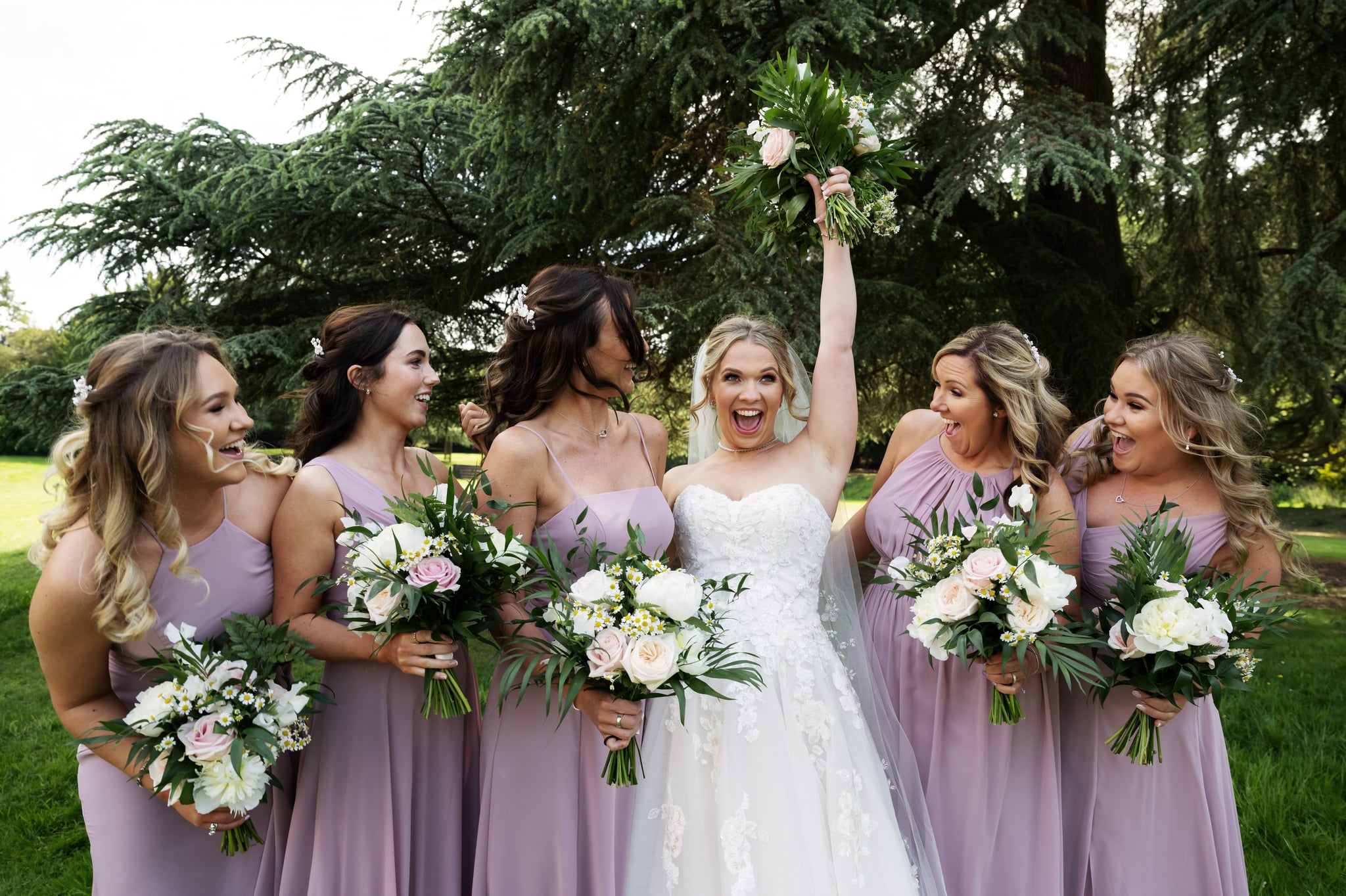 The Bride gives a big chair during a group photo of her and her bridesmaids.