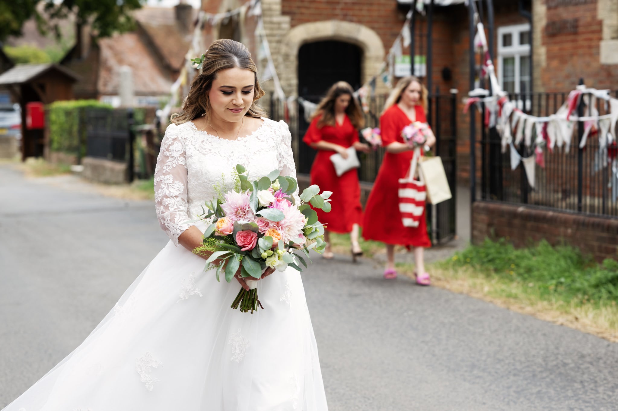 The Bride walking towards the church with her bridesmaids in the background