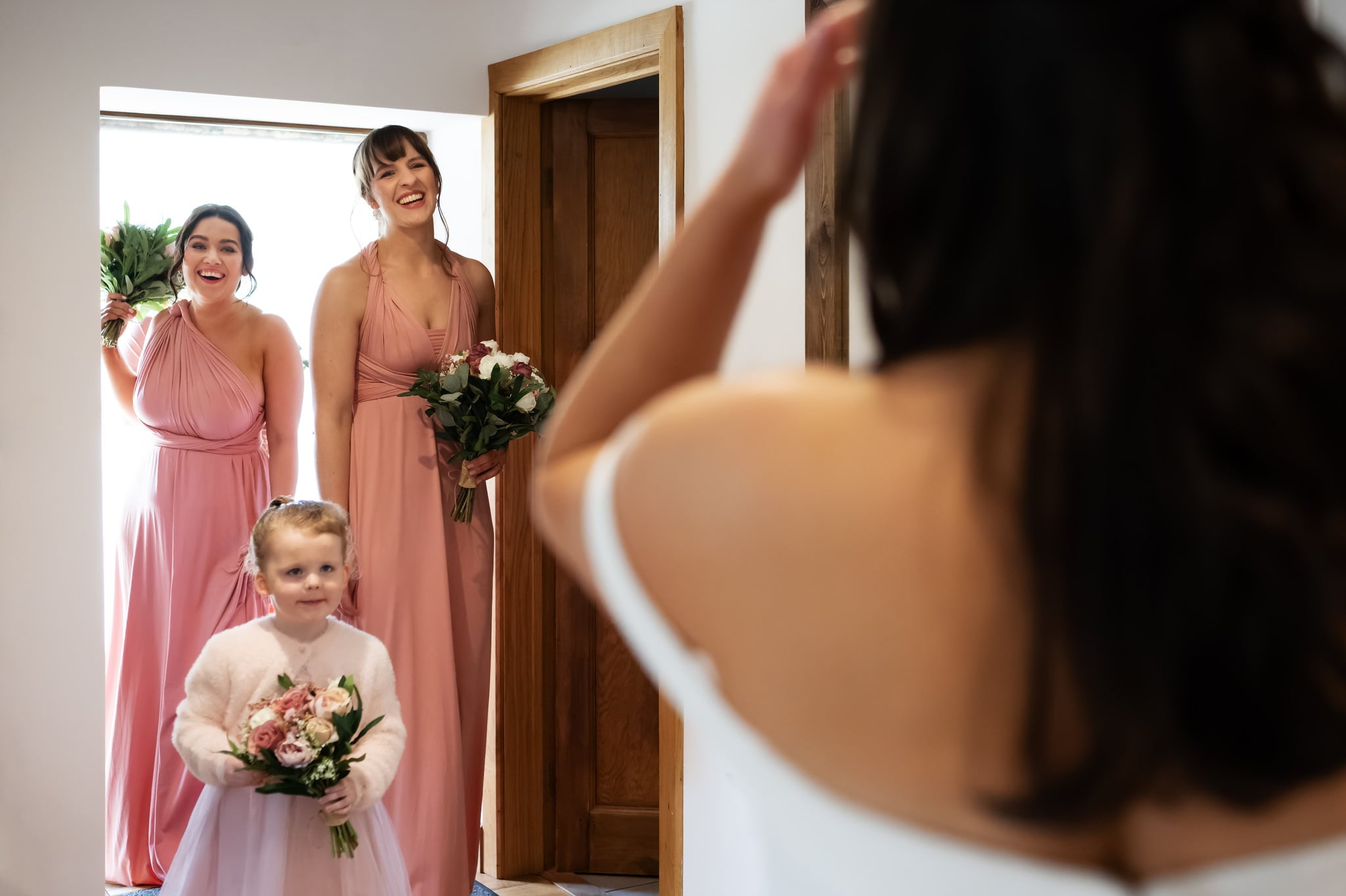 Bride and bridesmaids looking at each other in the mirror.