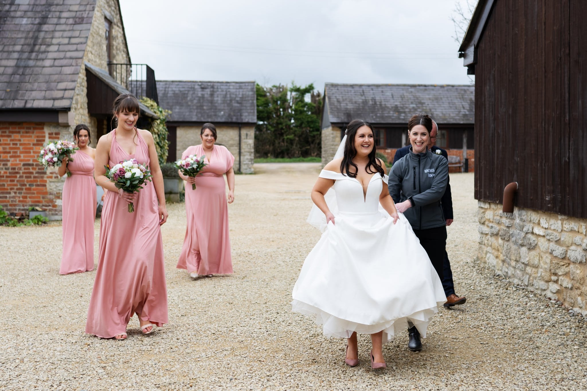 A bride and her bridesmaids gracefully navigate through a barn at Huntsmill Farm captured by the talented wedding photographer.