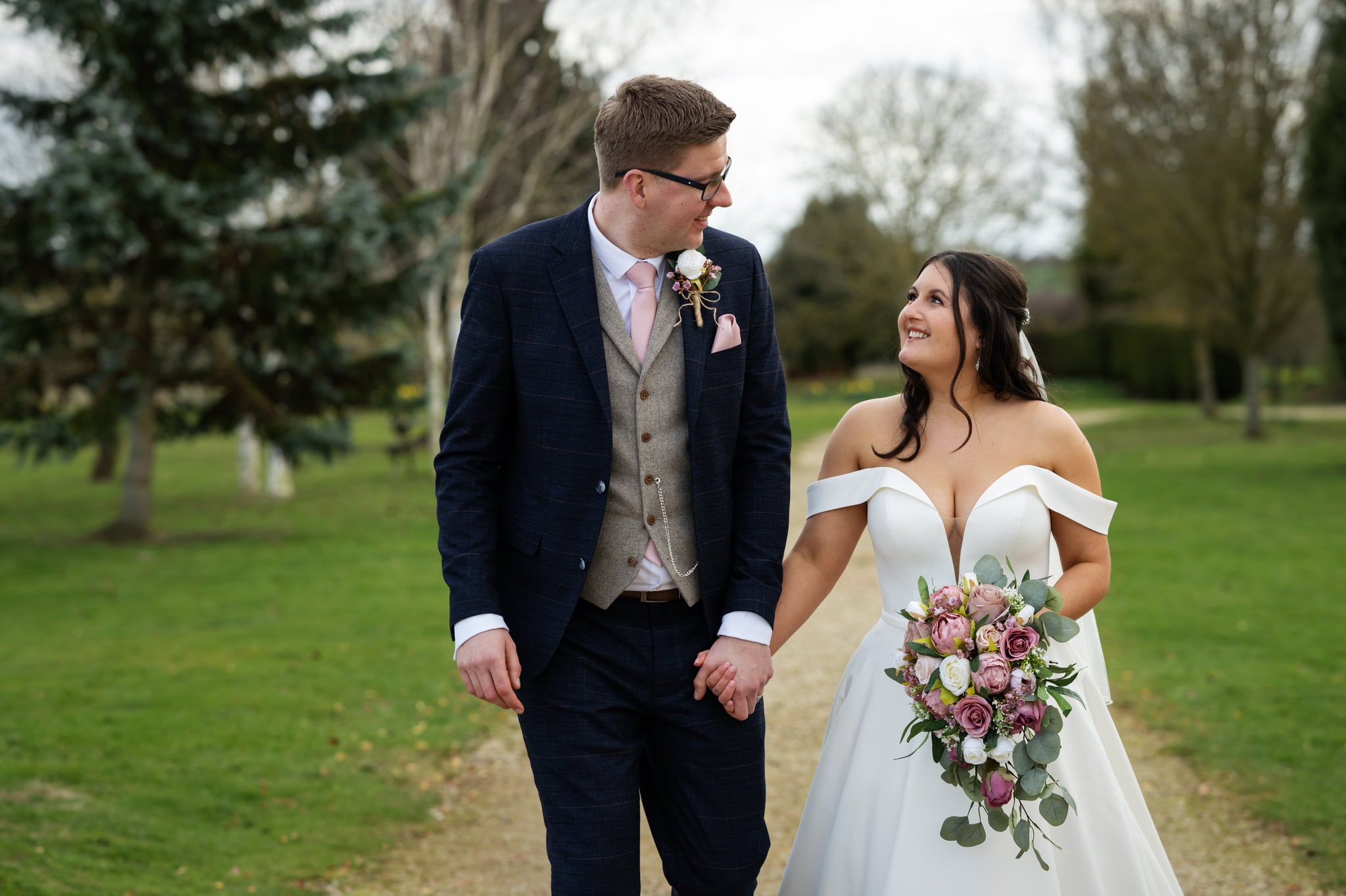 A bride and groom captured by a Huntsmill Farm wedding photographer as they stroll through a park.
