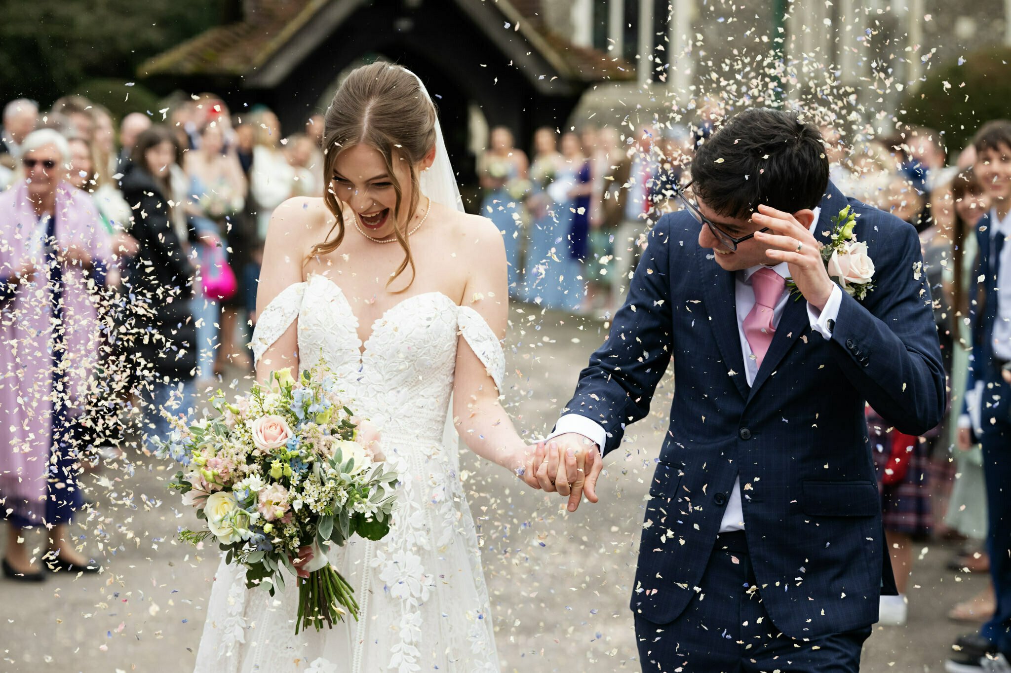 A bride and groom captured in natural wedding photography, gracefully walking down the aisle with confetti swirling around them.