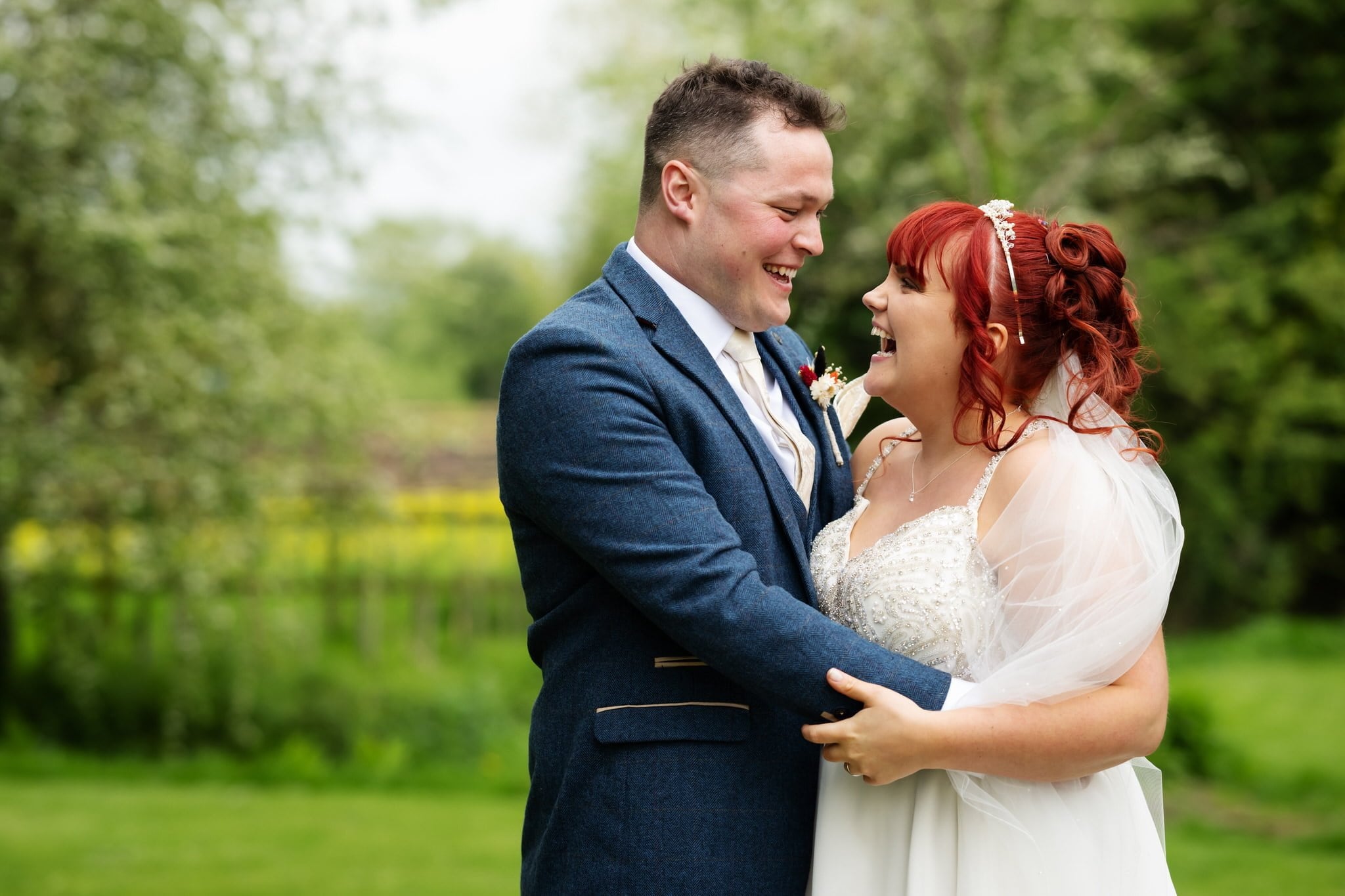 A bride and groom smiling in a field at Crazy Bear Stadhampton.