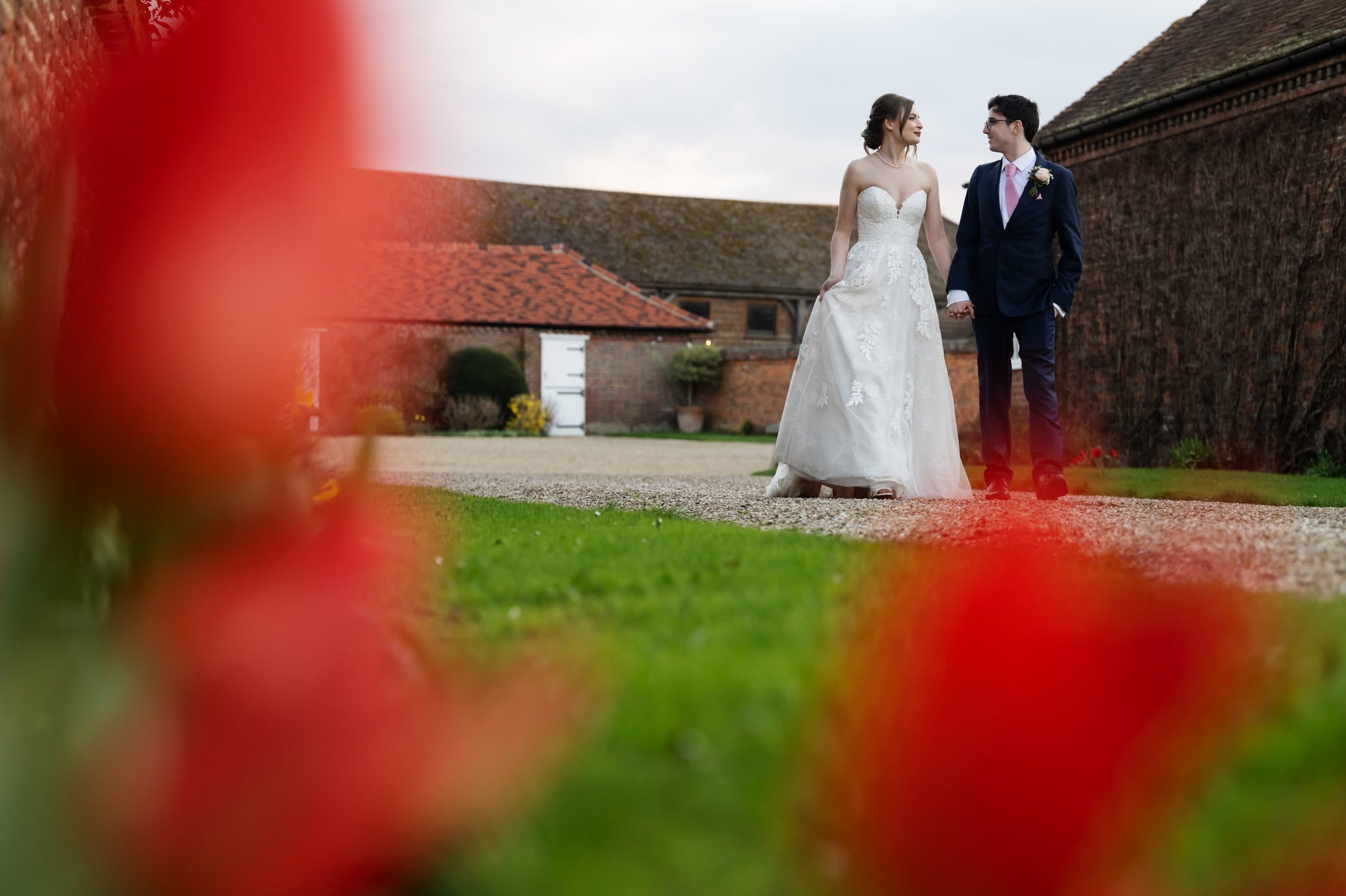 A bride and groom captured by a Lillibrooke Manor Wedding Photographer amidst red tulips.