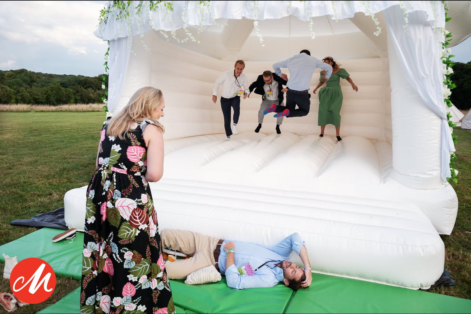 A group of people playing in an inflatable bounce house at a natural-themed wedding.