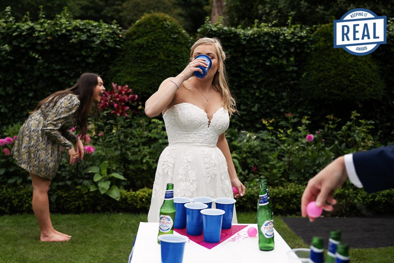 A natural wedding photography capturing a playful bride and groom enjoying a game of beer pong.