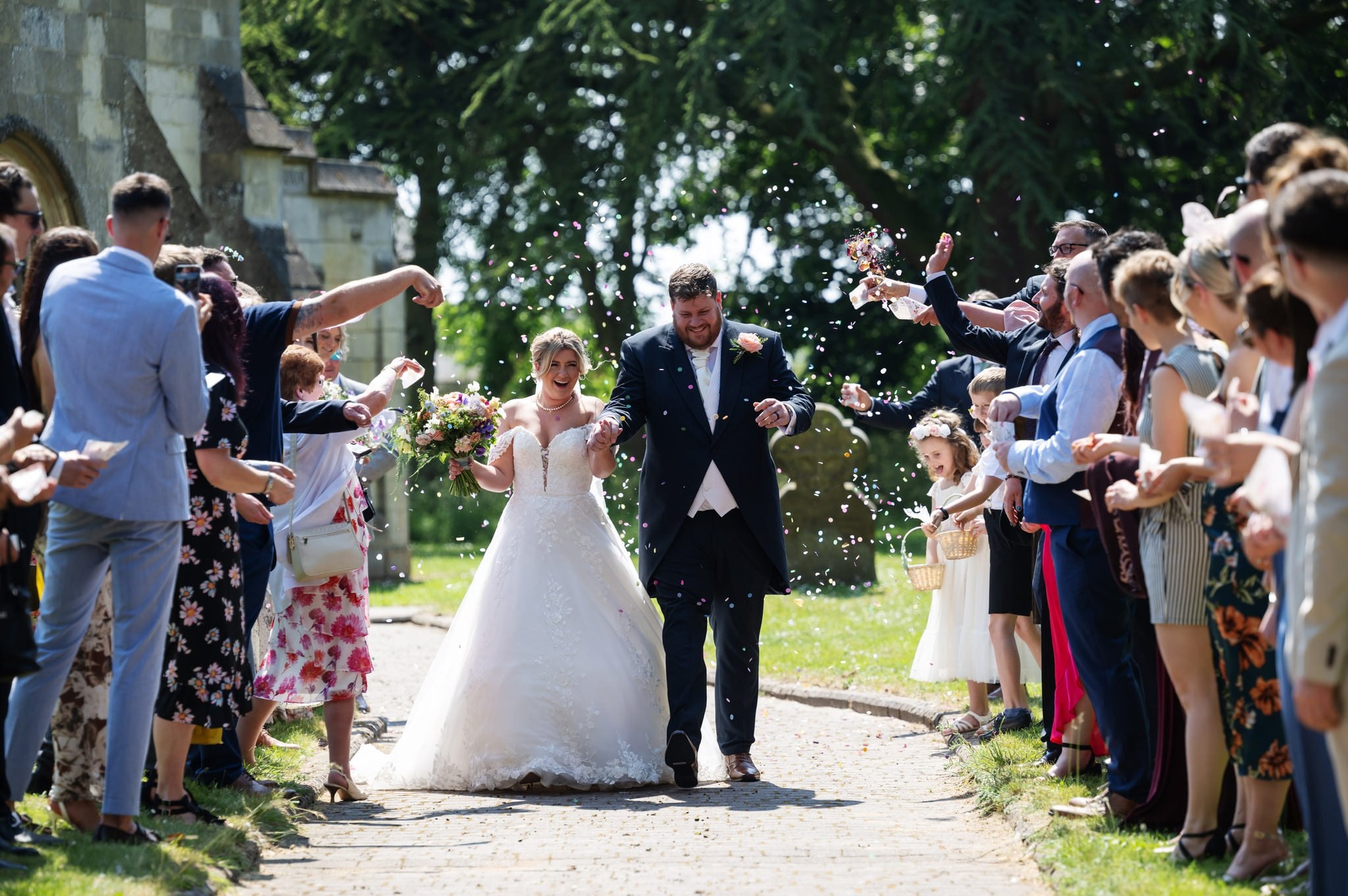 A bride and groom walking down a path with confetti thrown at them.