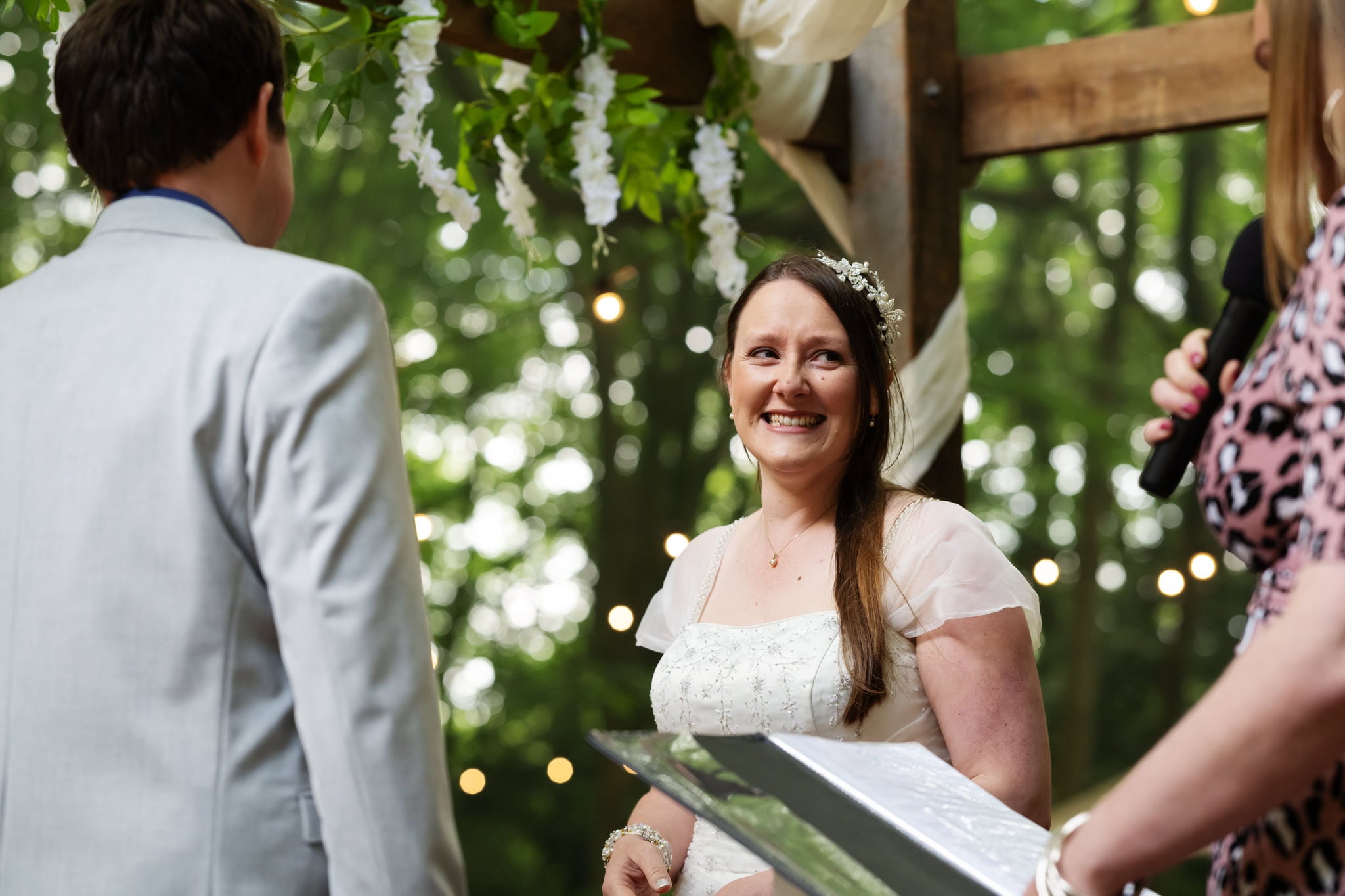 A bride and groom smiling at each other during their wedding ceremony.