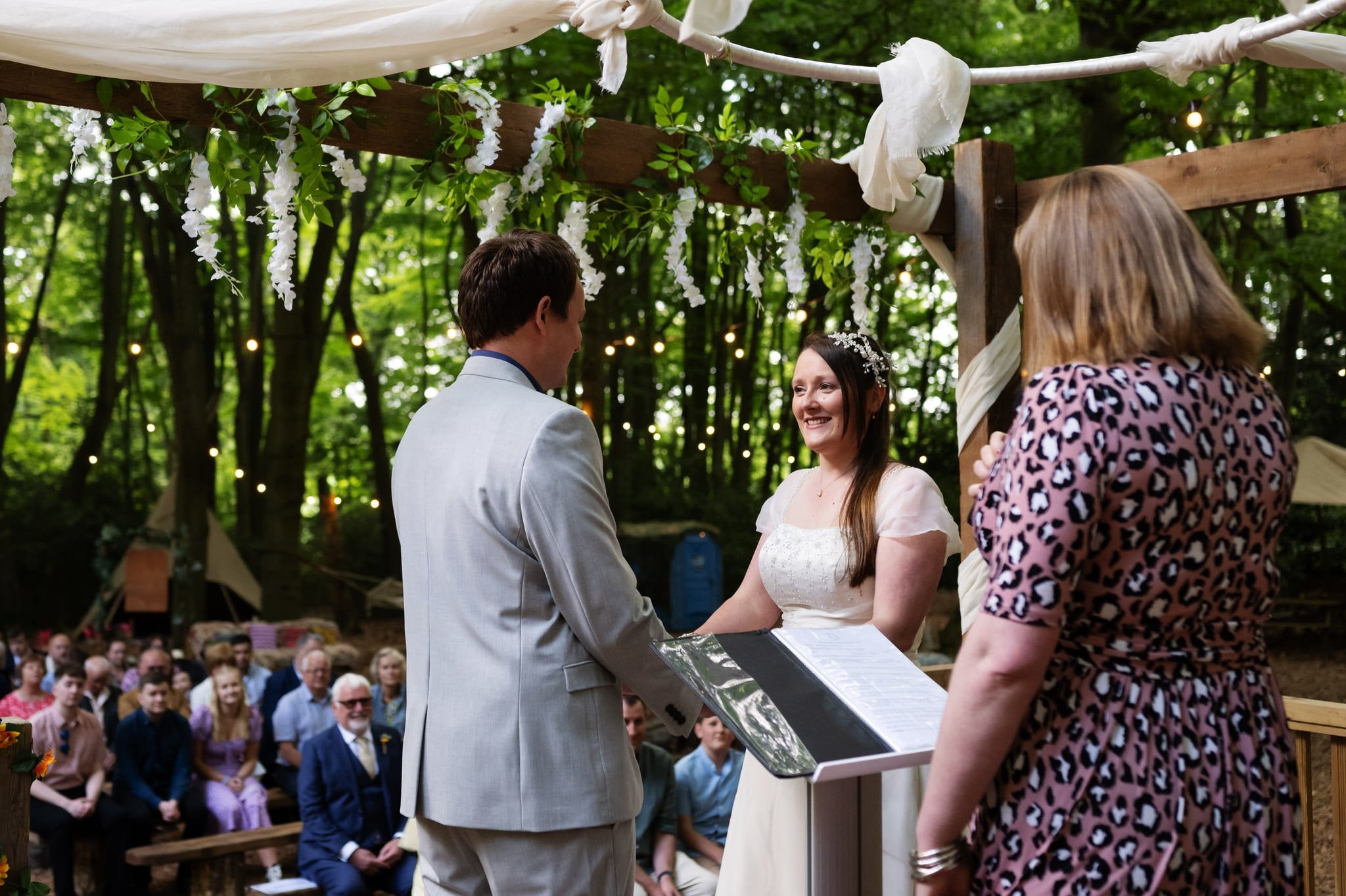 A bride and groom exchange vows in the woods.