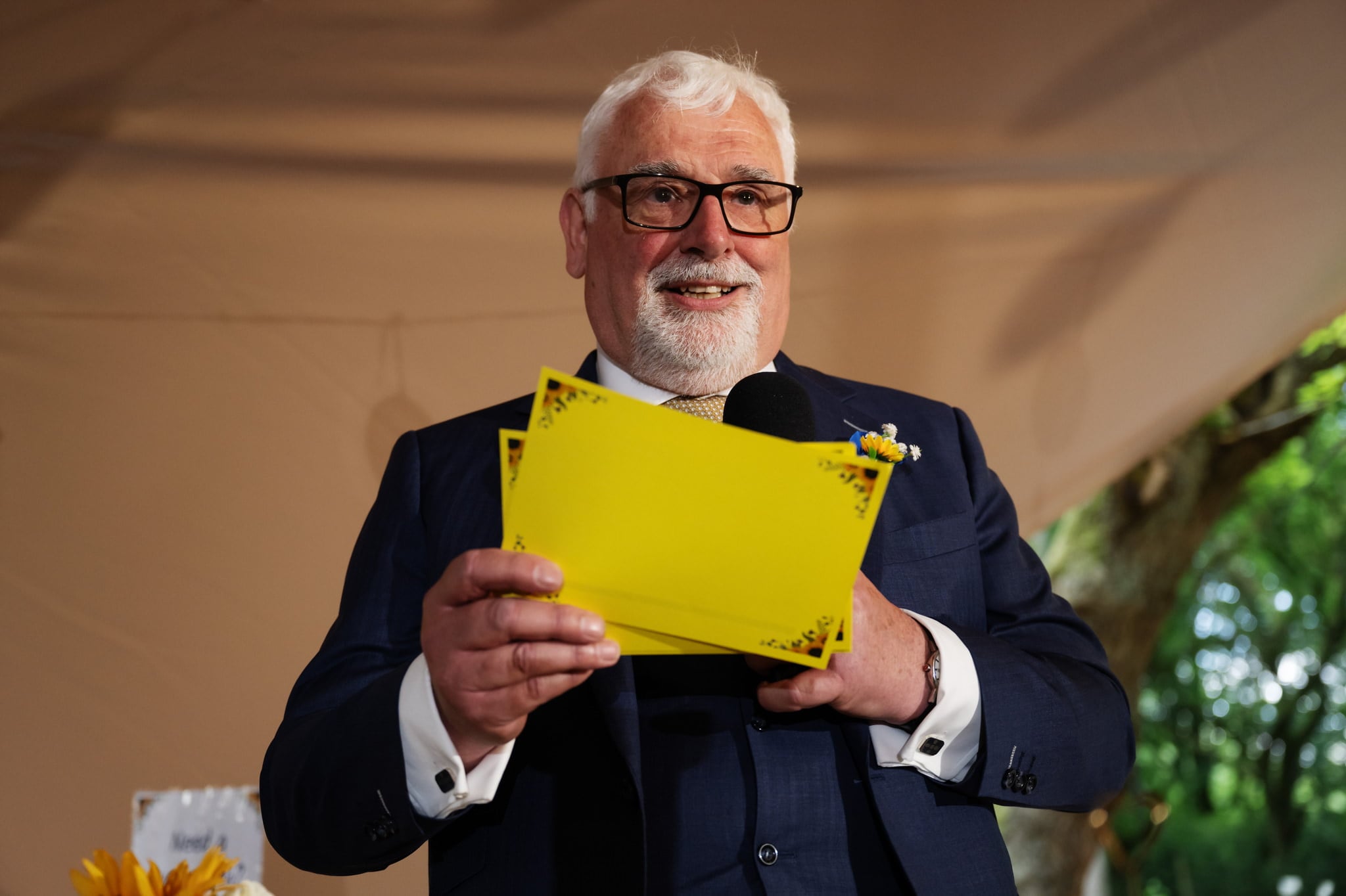A man in a suit holding a yellow piece of paper.