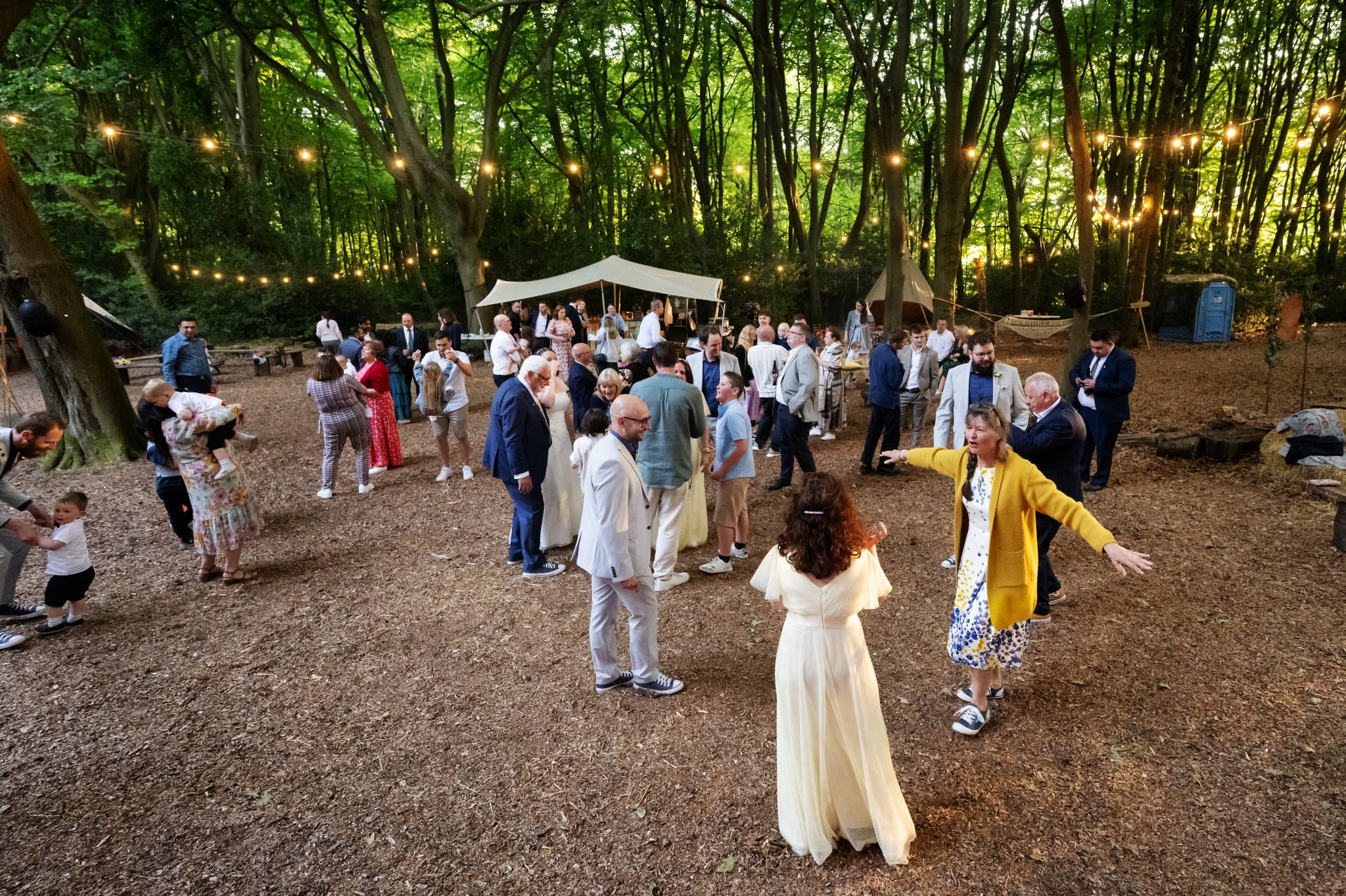 A group of people dancing in a wooded area.