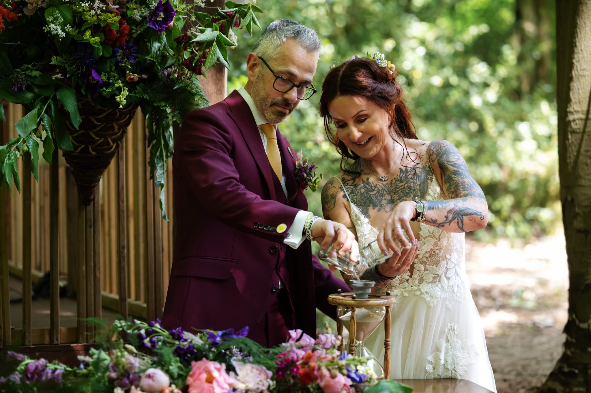 A bride and groom lighting a candle in the woods.