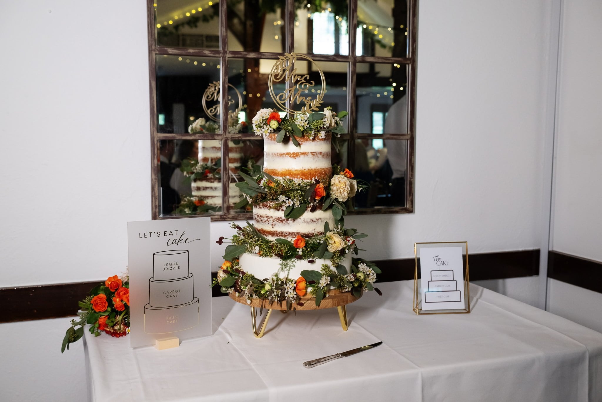 A wedding cake sitting on a table in front of a mirror.