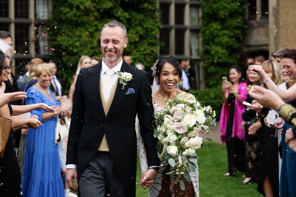Bride and groom walking through confetti at Fanhams Hall