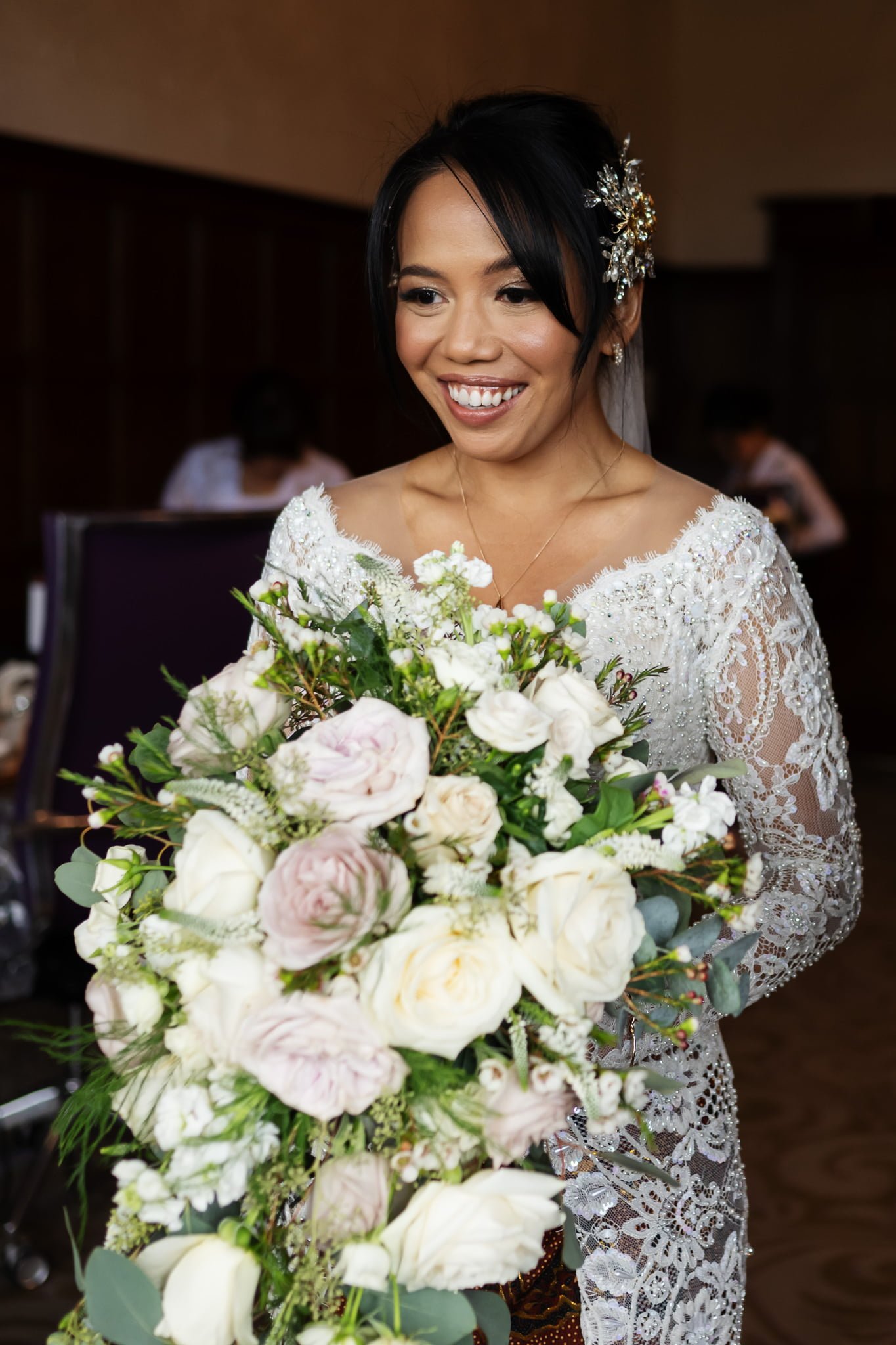 A bride smiles as she holds her wedding bouquet.