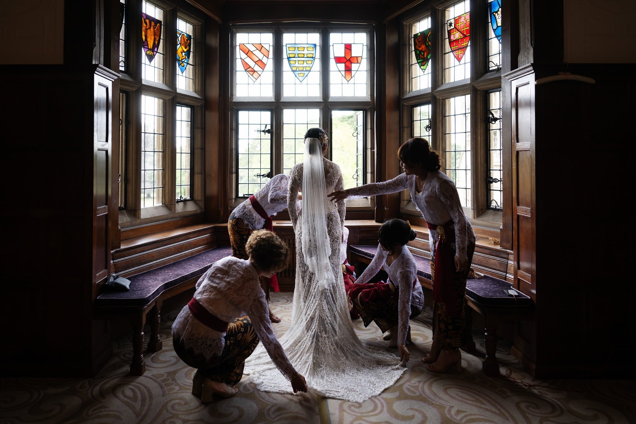 A bride is getting ready in a room with stained glass windows.