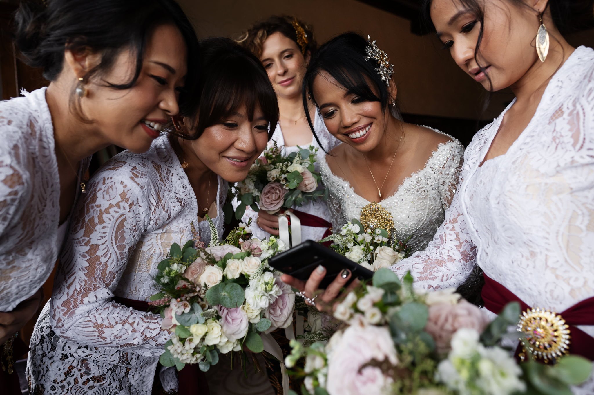 A group of bridesmaids looking at a cell phone.