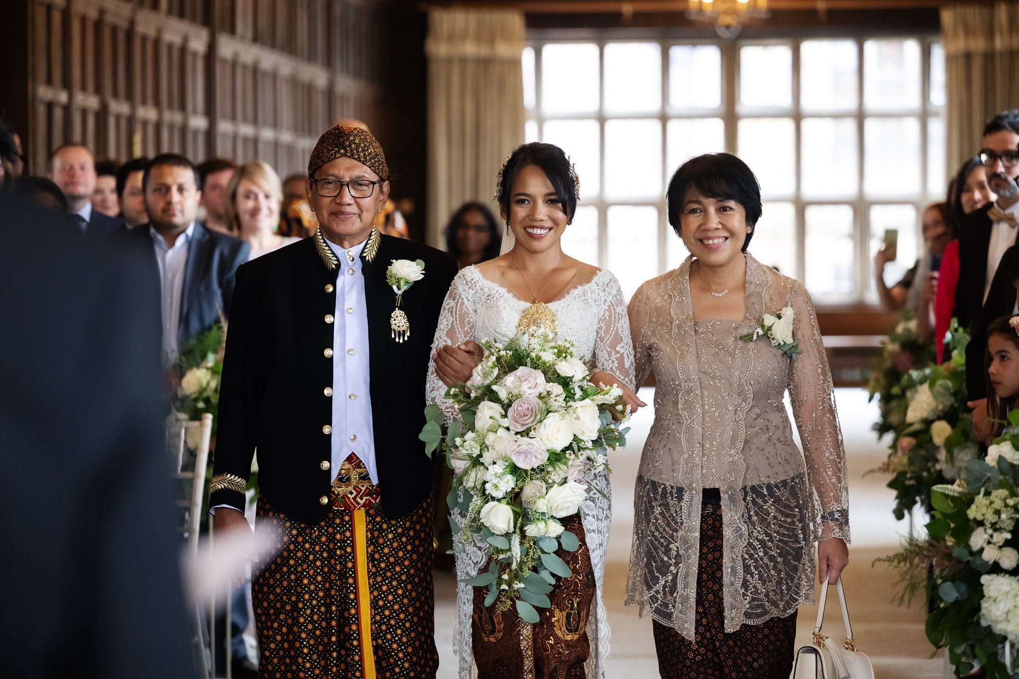 A bride and her mother walk down the aisle at an indonesian wedding.
