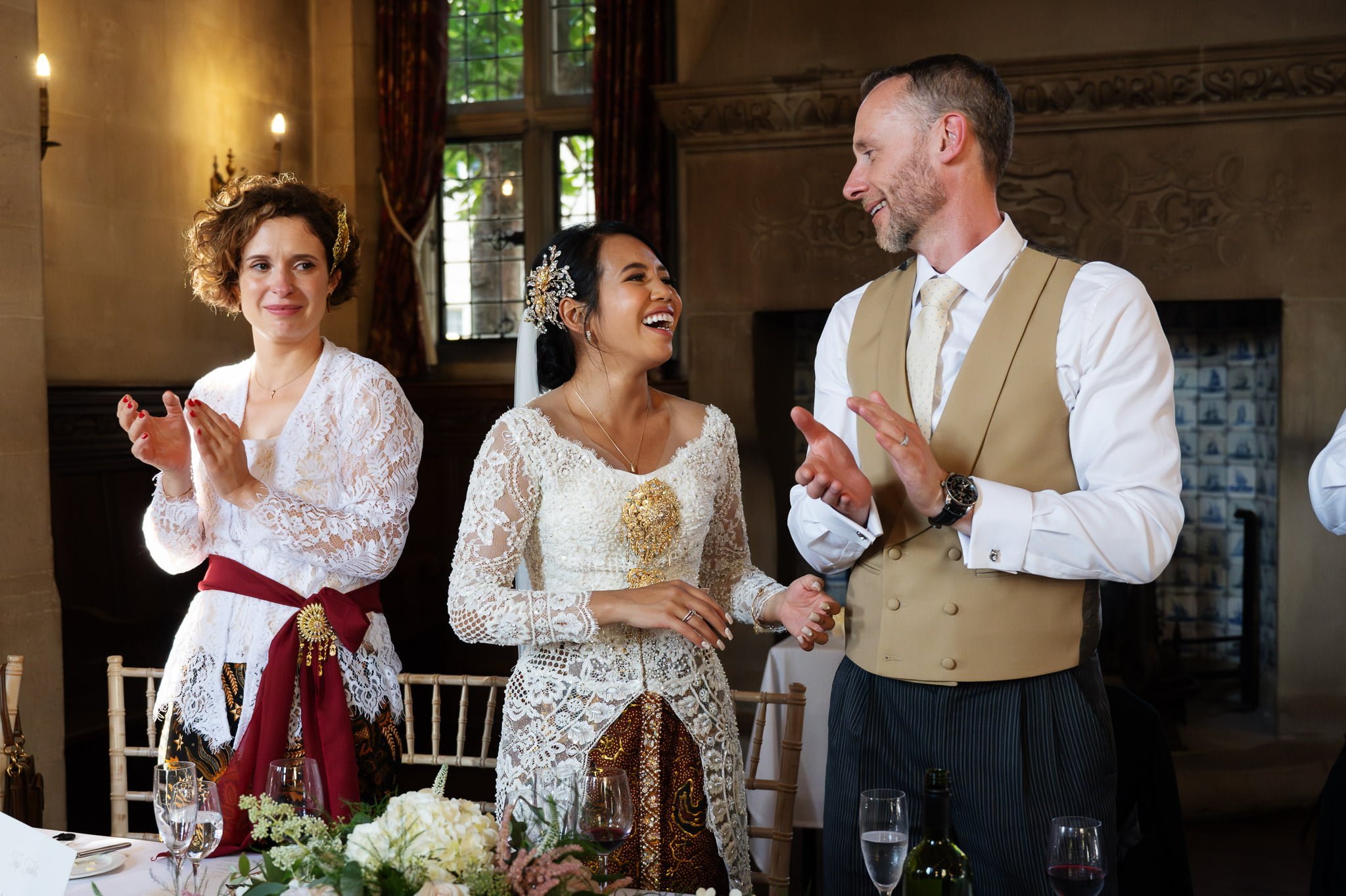 A bride and groom clapping at a wedding reception.