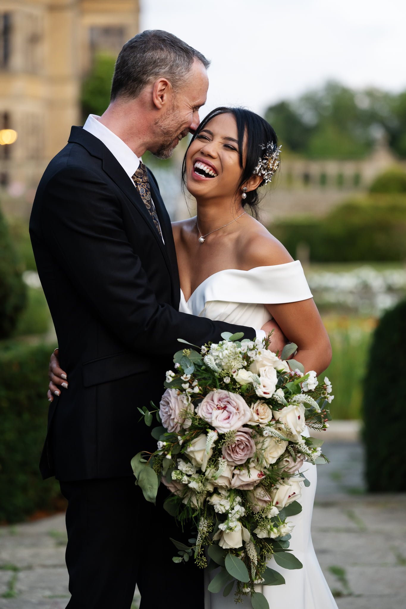 A bride and groom kissing in front of a castle.