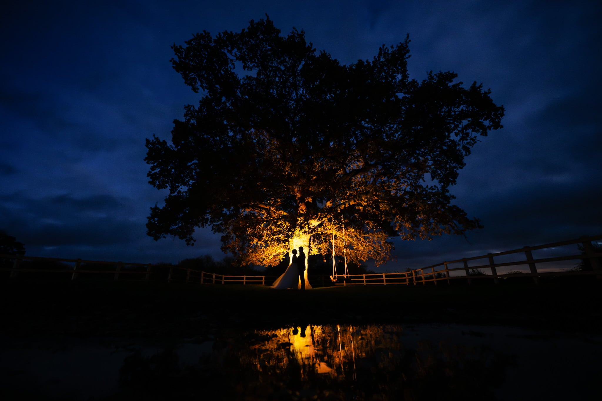 A silhouette of the bride and groom by the Oak Tree at Milling Barn wedding