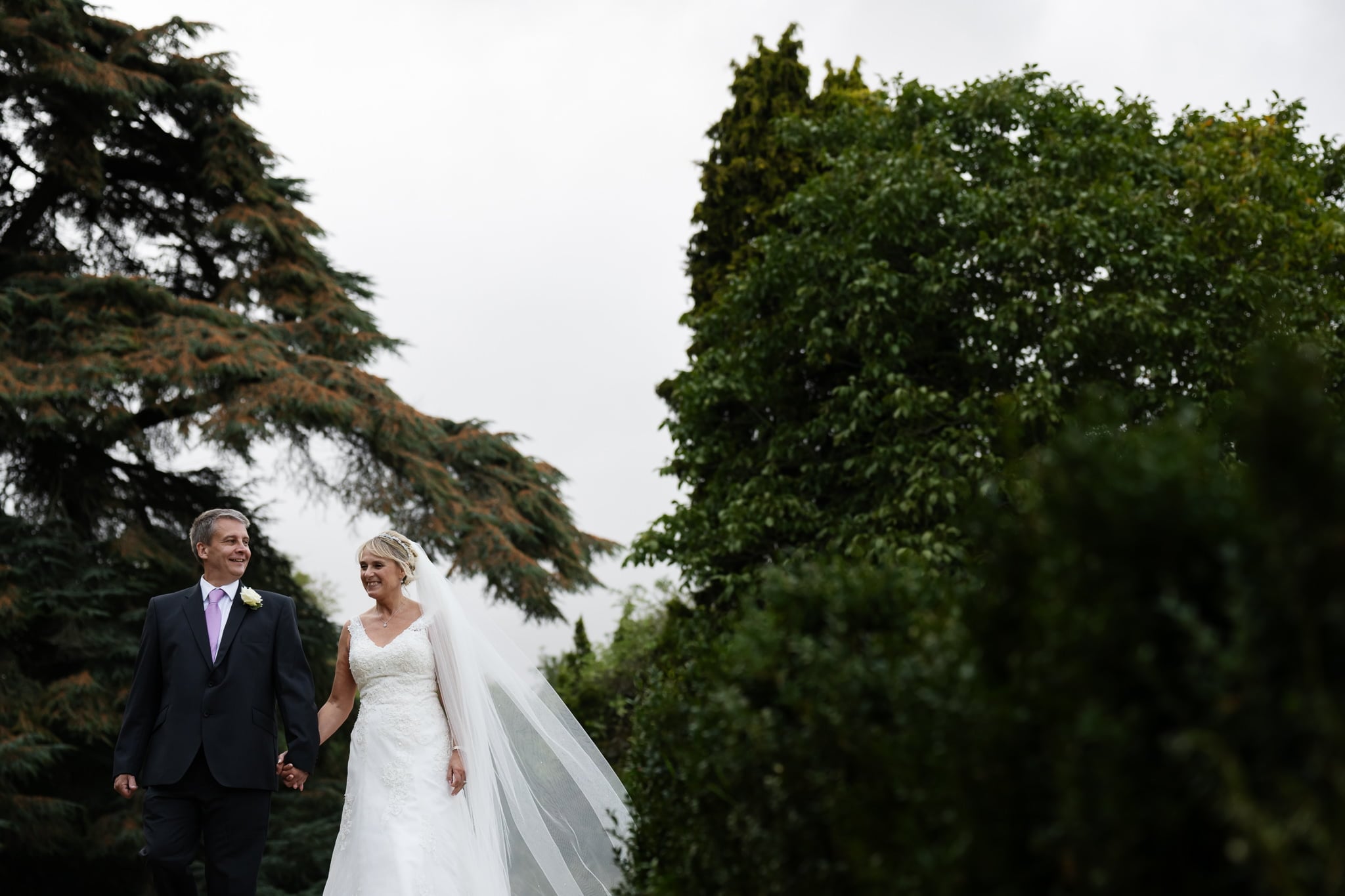 Bride and groom walking in the grounds of Pendley Manor
