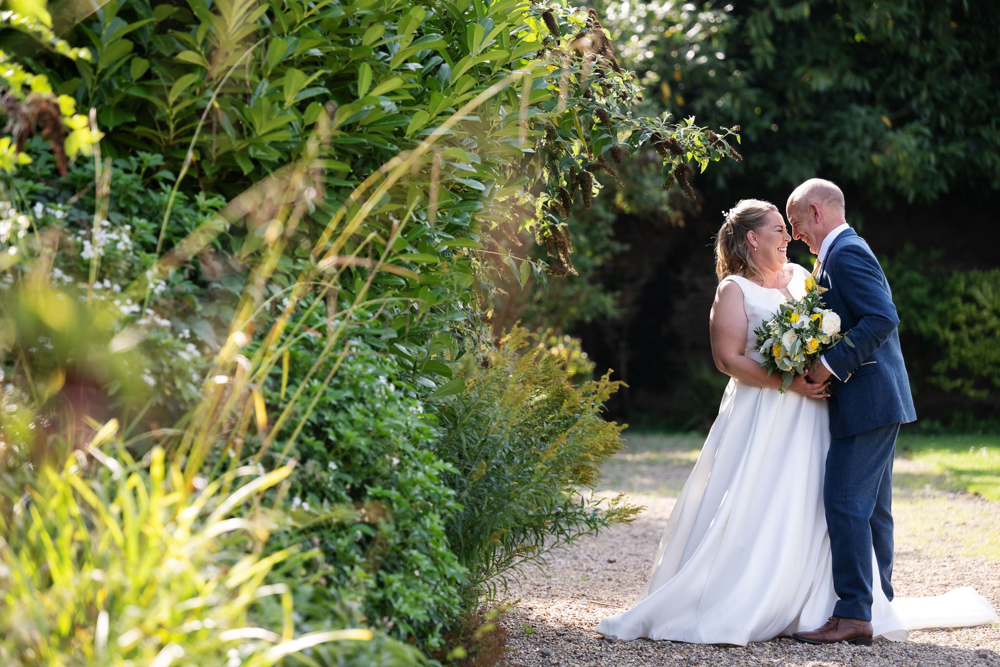 A bride and groom kissing in a garden.