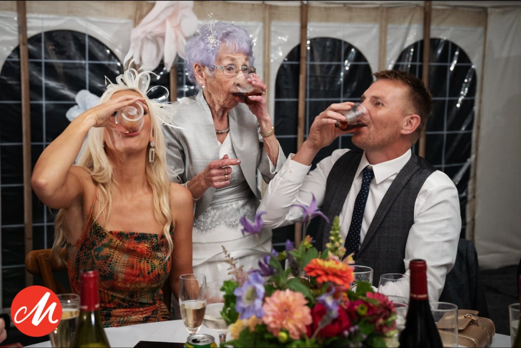 Three people having Jager Bomb shots at a wedding, captured by a Hertfordshire wedding photographer. Masters of Wedding Photography